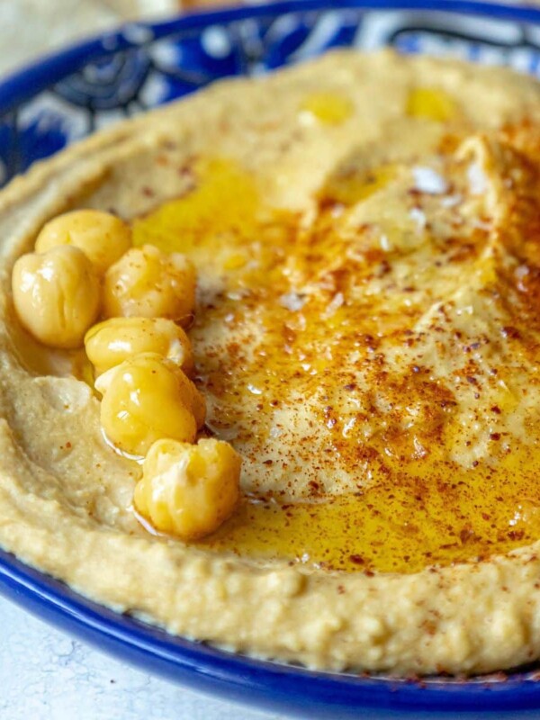 picture of hummus topped with sumac, chickpeas, and olive oil in a blue bowl