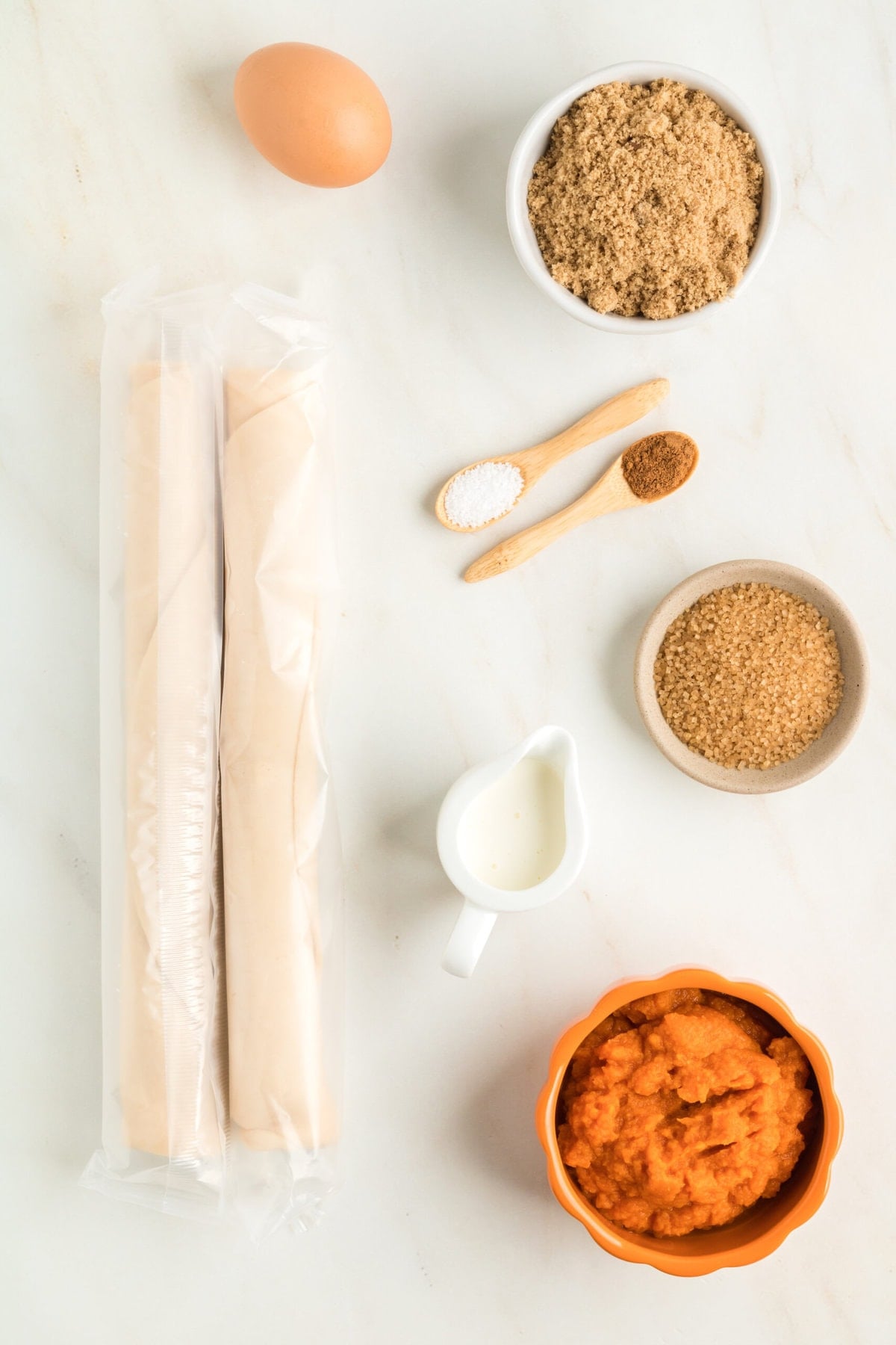 picture of pastry dough, pumpkin, milk, sugar, and spices on a table
