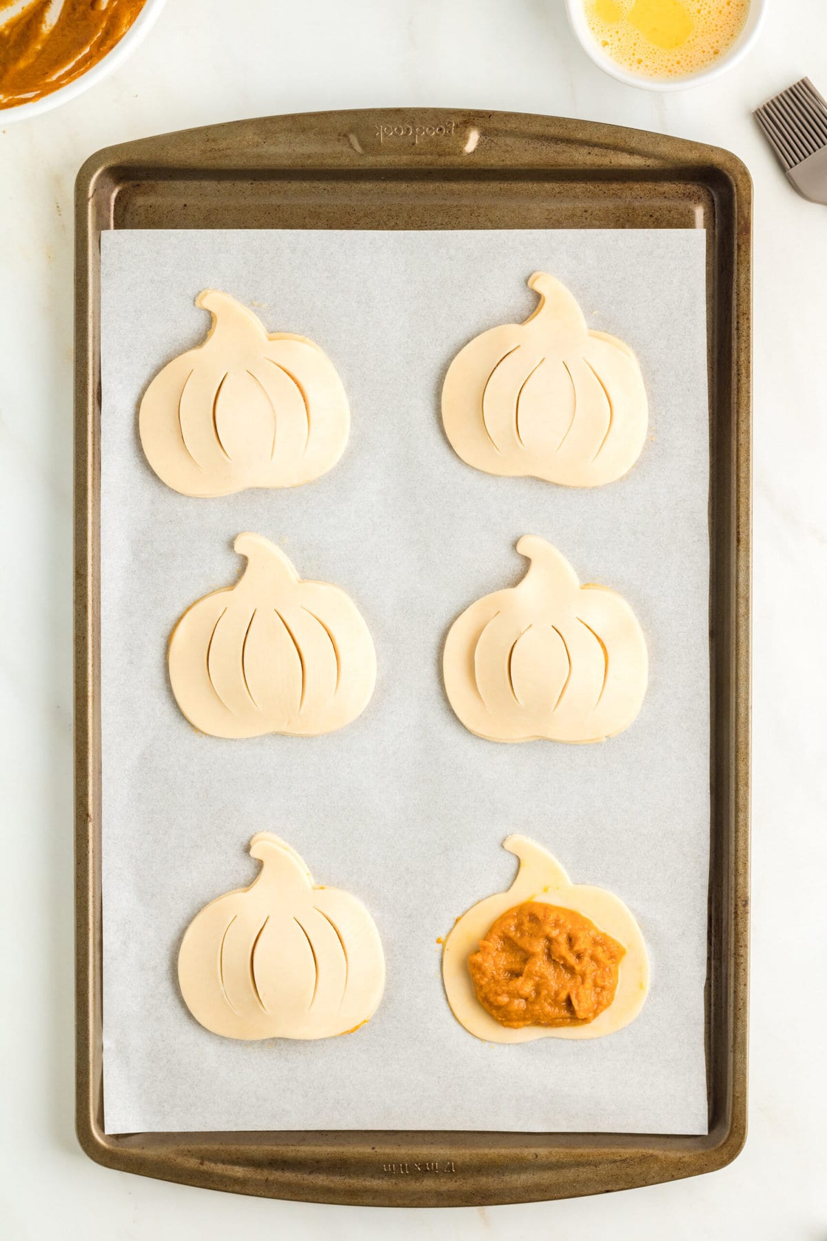 picture of pumpkin pie filling in dough on a baking sheet lined with parchment paper