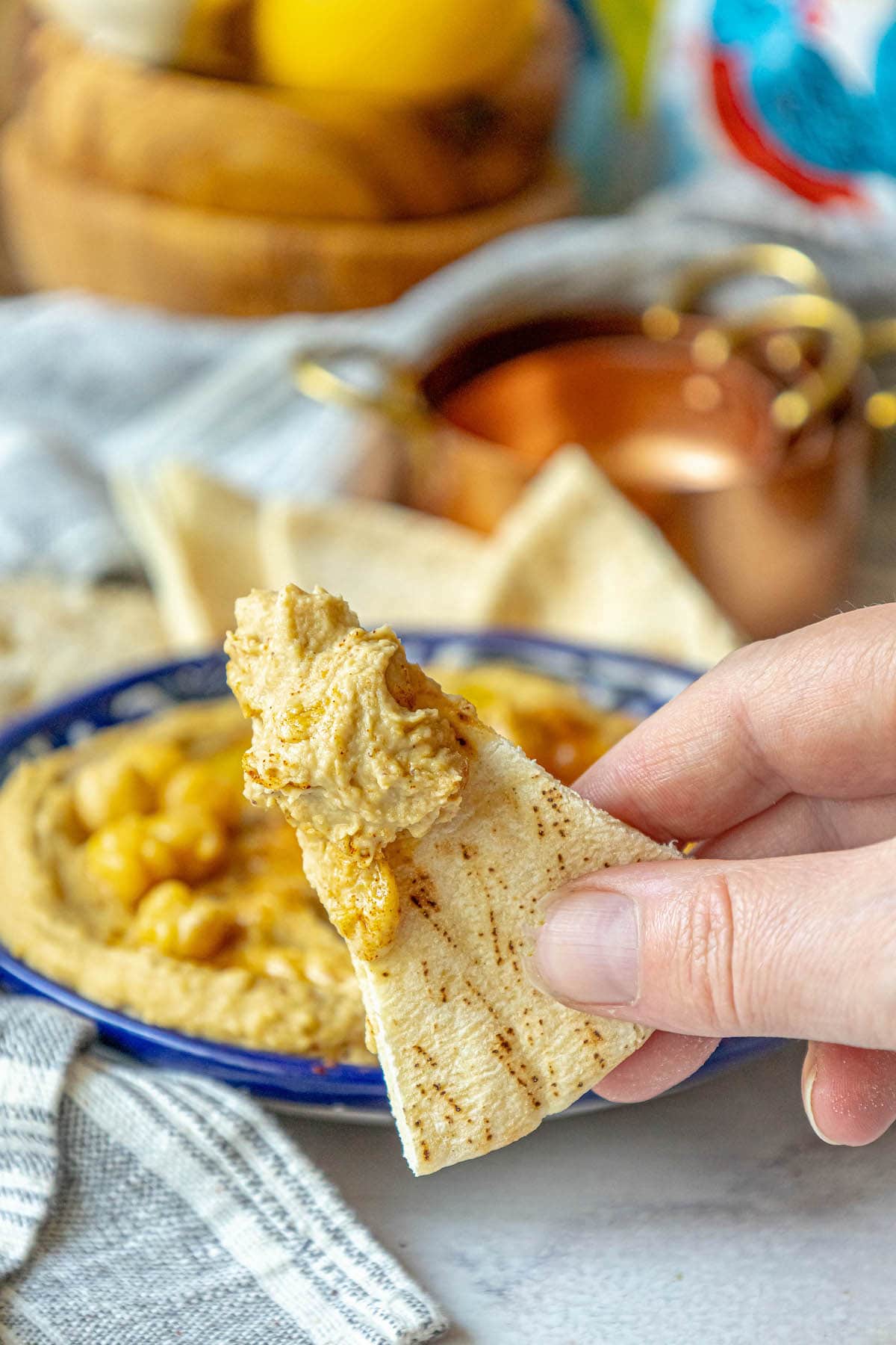 picture of hummus topped with sumac, chickpeas, and olive oil in a blue bowl 