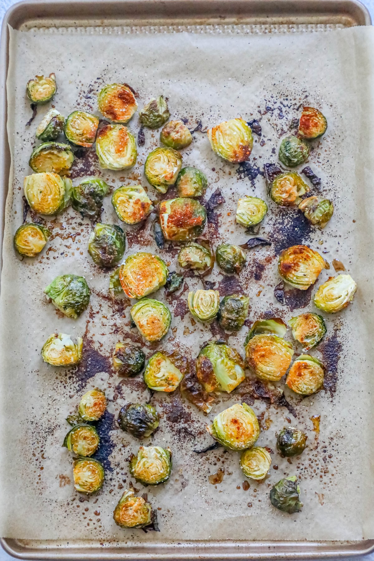 picture of roasted garlic brussels sprouts that are seasoned on a baking sheet lined with parchment paper