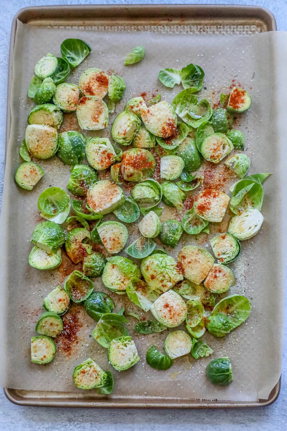 picture with seasoned brussels sprouts on a baking sheet lined with parchment paper