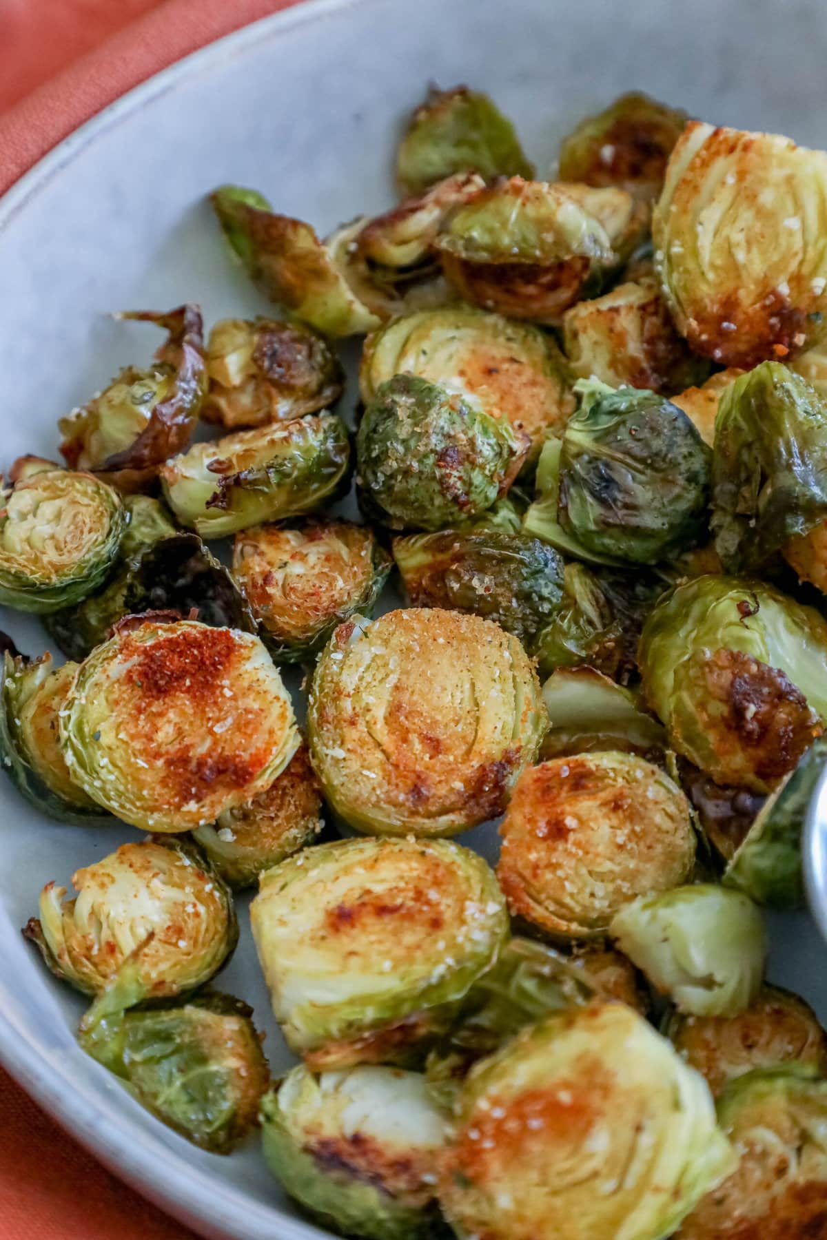 picture of garlic roasted brussels sprouts in a white bowl with a cup of sauce