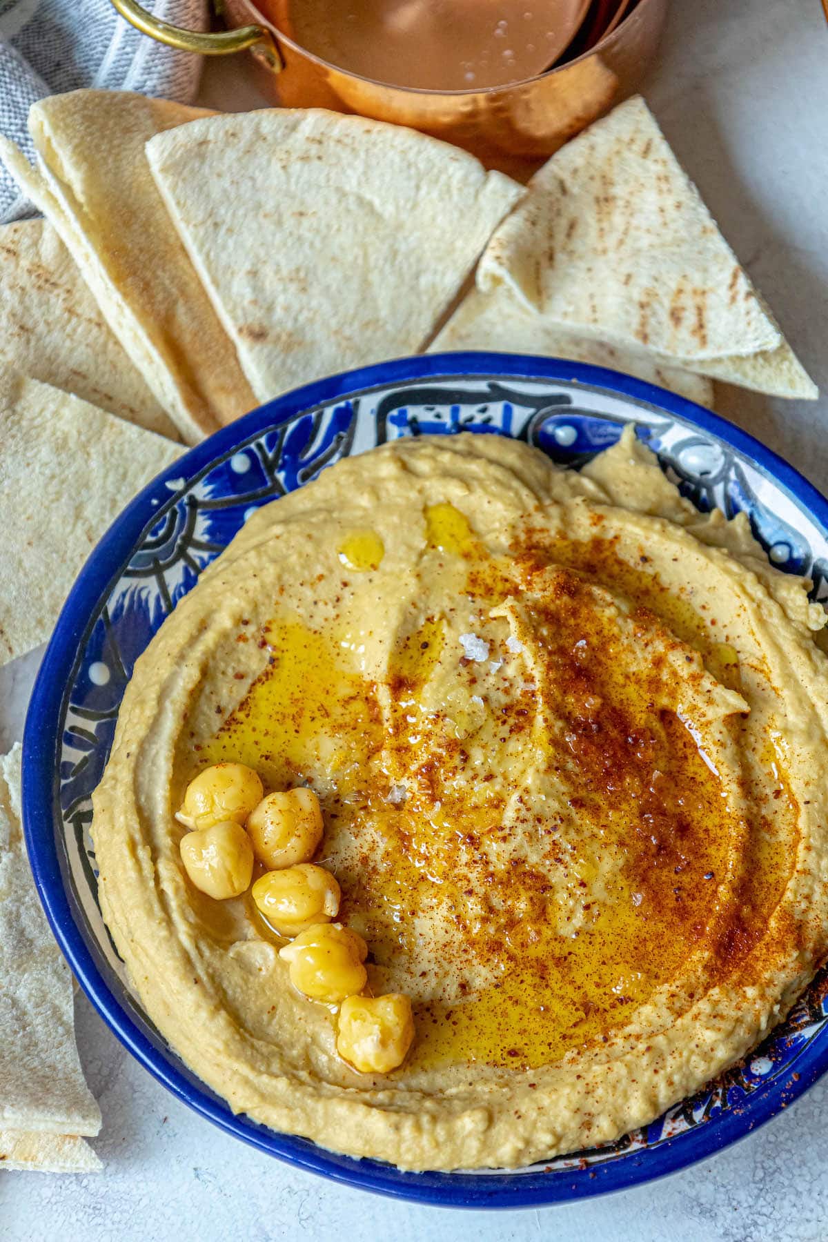 picture of hummus topped with sumac, chickpeas, and olive oil in a blue bowl 