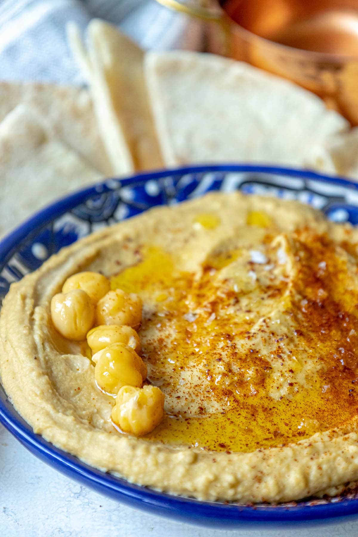 picture of hummus topped with sumac, chickpeas, and olive oil in a blue bowl 