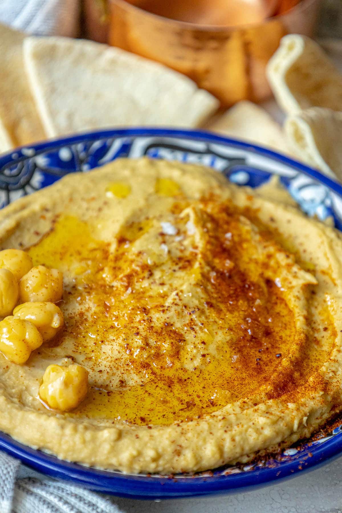 picture of hummus topped with sumac, chickpeas, and olive oil in a blue bowl 