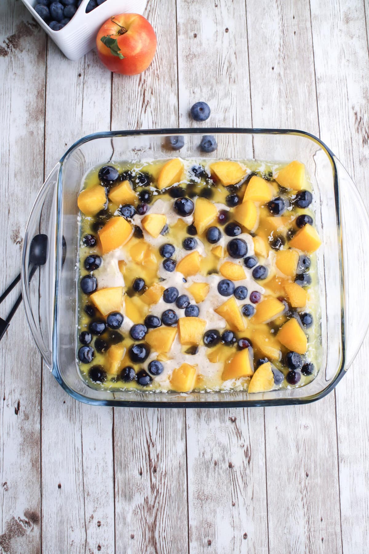 cobbler dough in a pan with blueberries and peaches