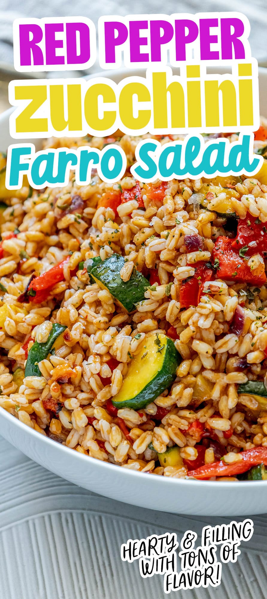 picture of farro salad in a white bowl with red peppers, zucchini, herbs, and shallots