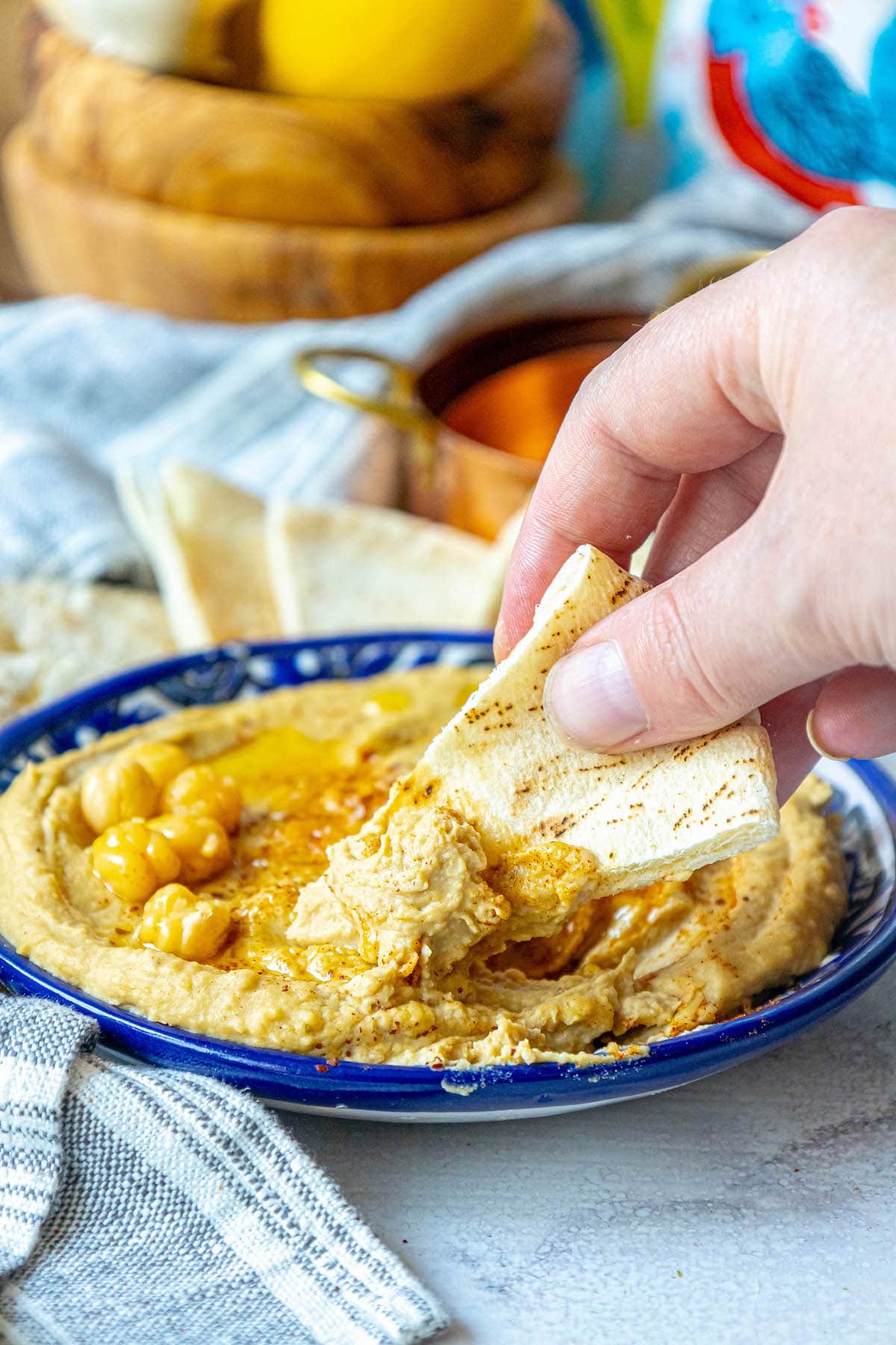 picture of hummus topped with sumac, chickpeas, and olive oil in a blue bowl 