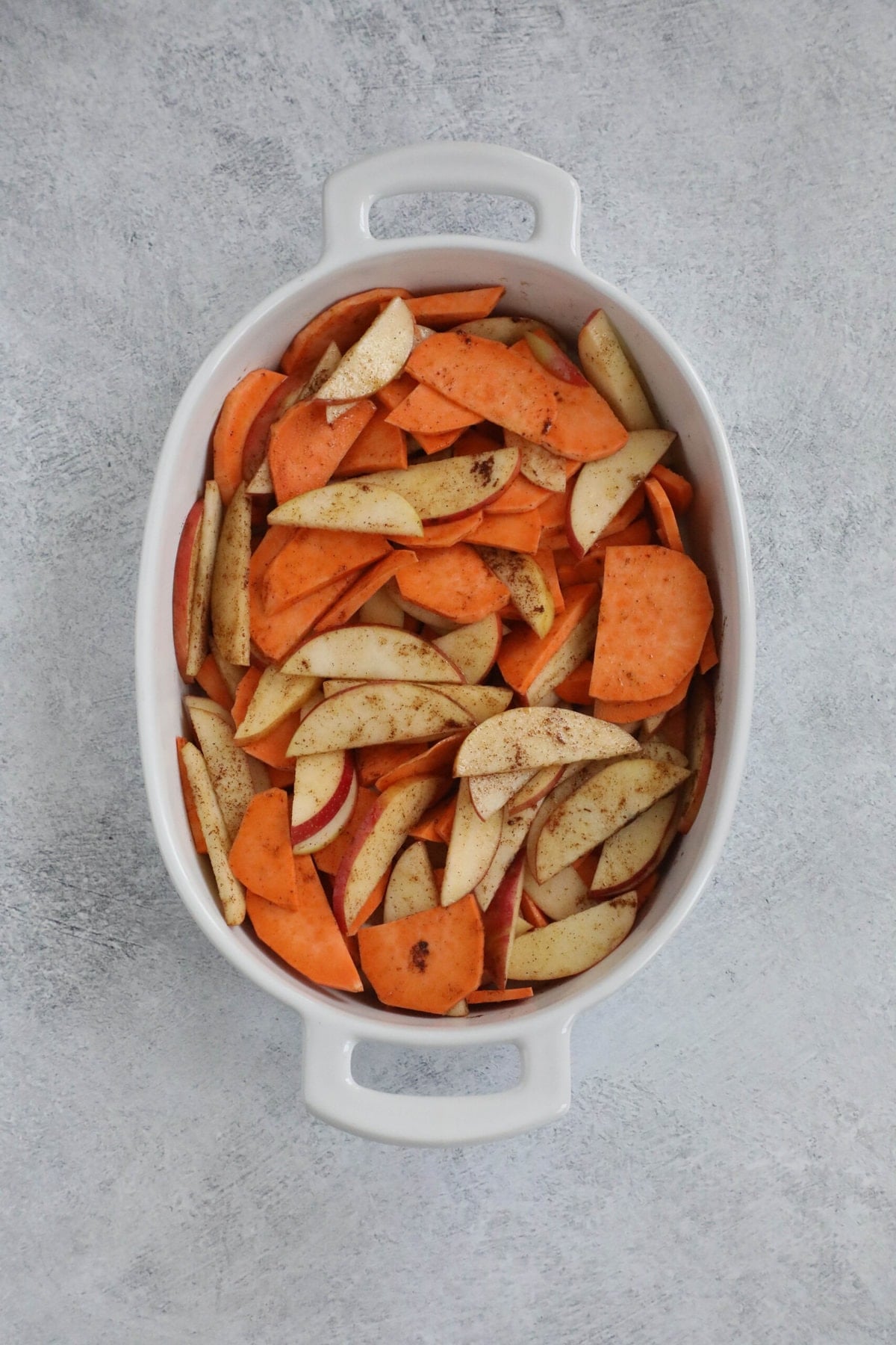 picture of apples and sweet potatoes seasoned with butter and cinnamon in a baking dish