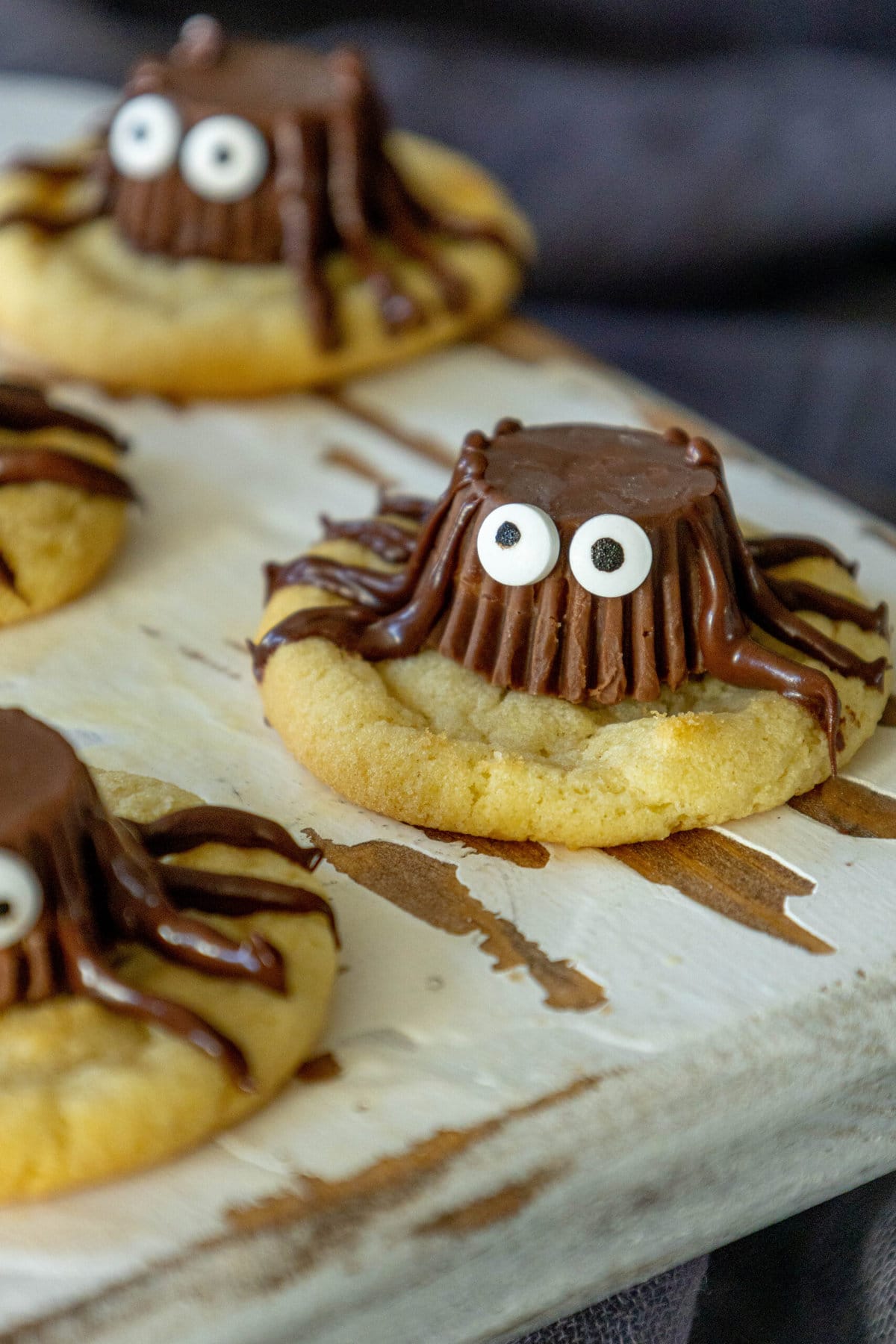 picture of cookies on a cutting board with peanut butter cups decorated to look like spiders on top
