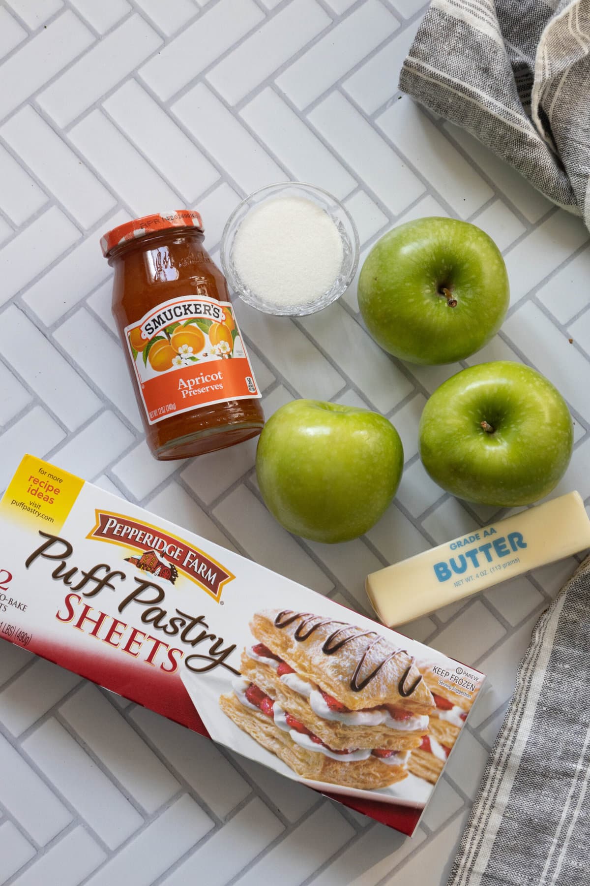 A counter with a box of apple pie filling, apples, and butter for easy French apple tarts.