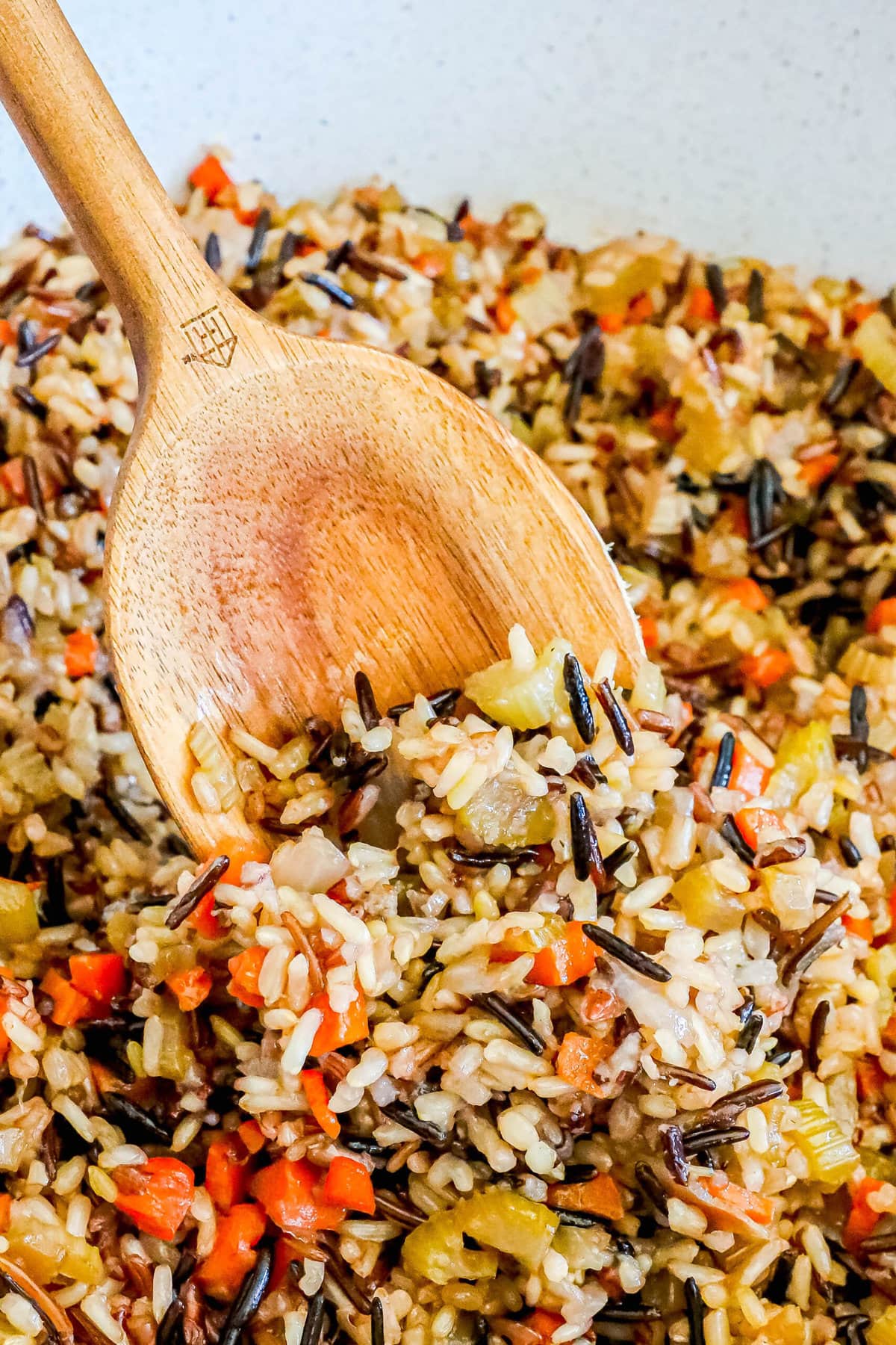 picture of a wooden spoon scooping rice pilaf from a white bowl 