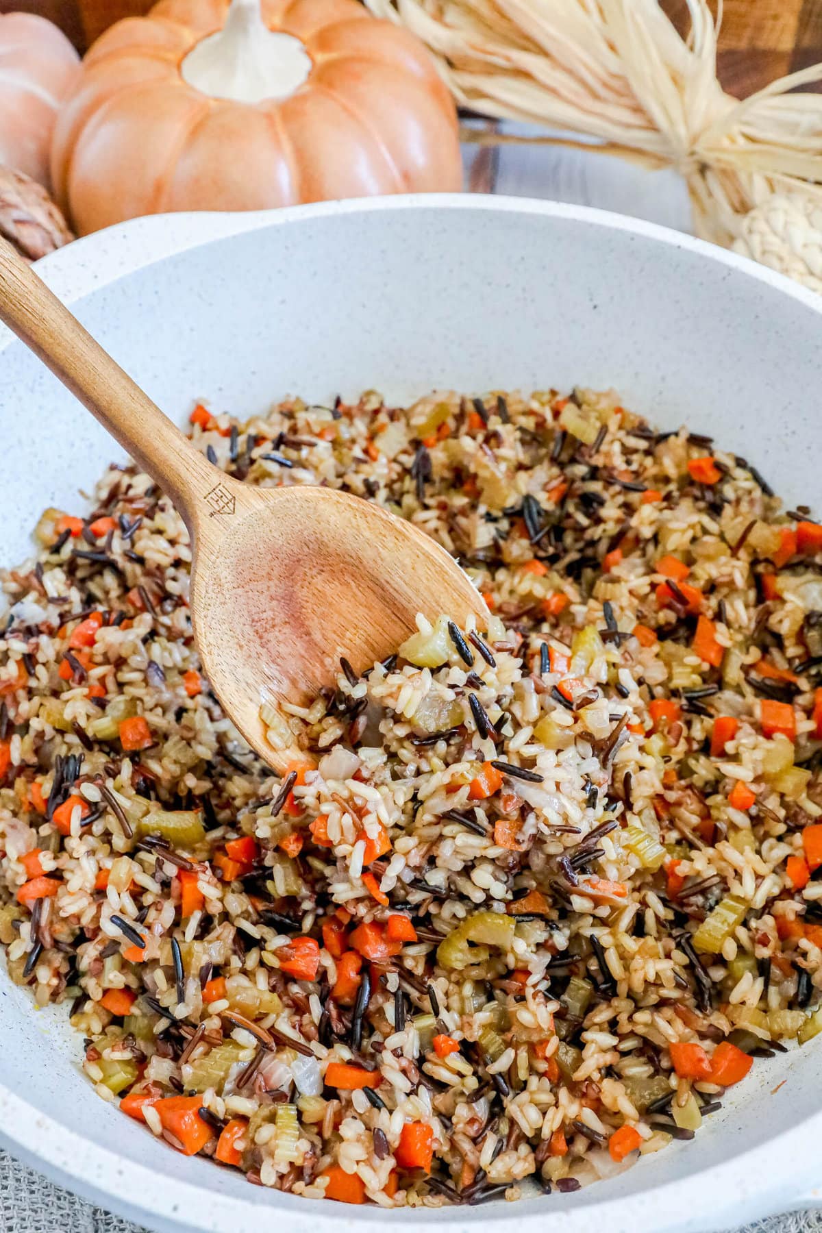 picture of a wooden spoon scooping rice pilaf from a white bowl 