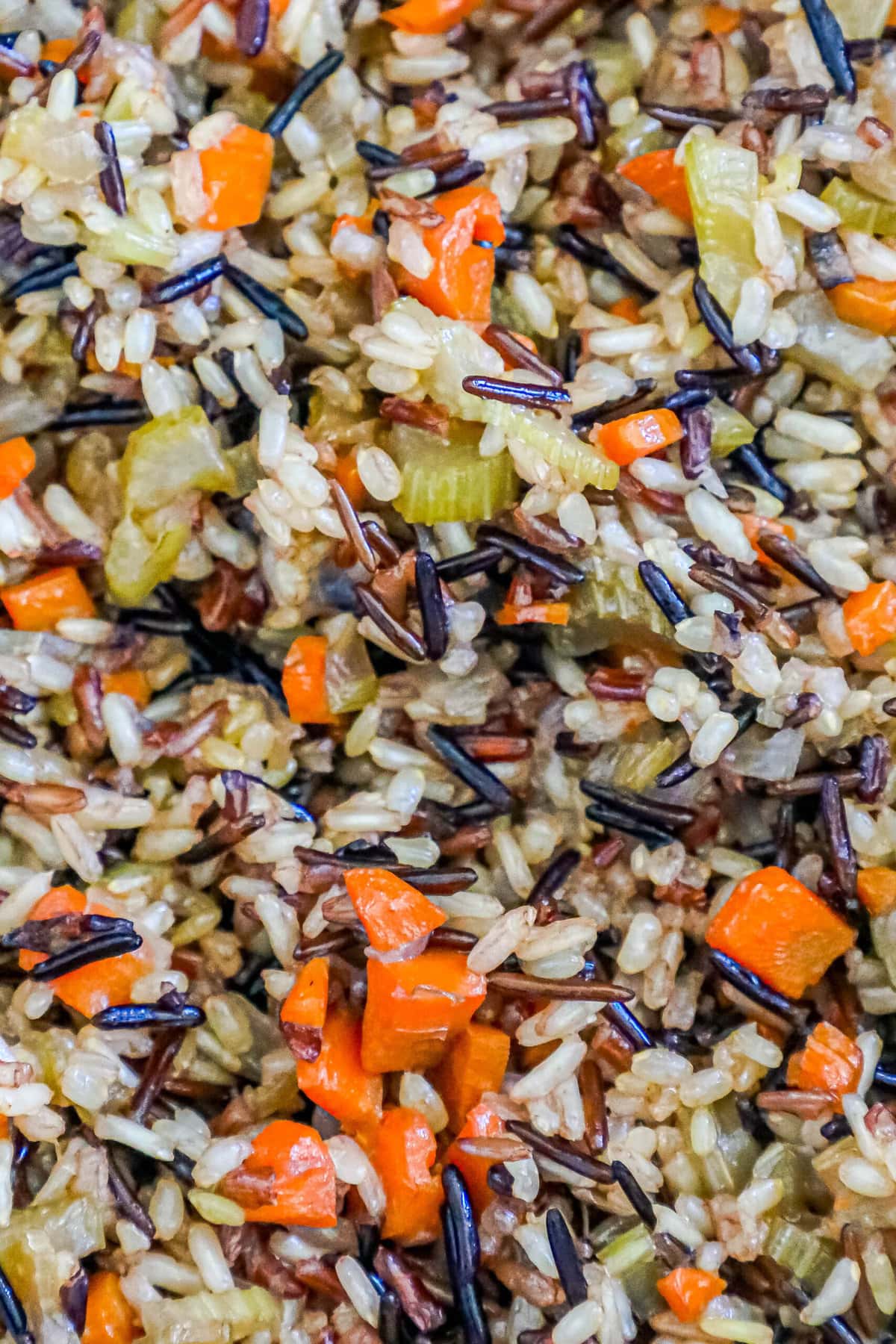 picture of wild rice pilaf up close with celery, onions, and carrots in the grains of rice