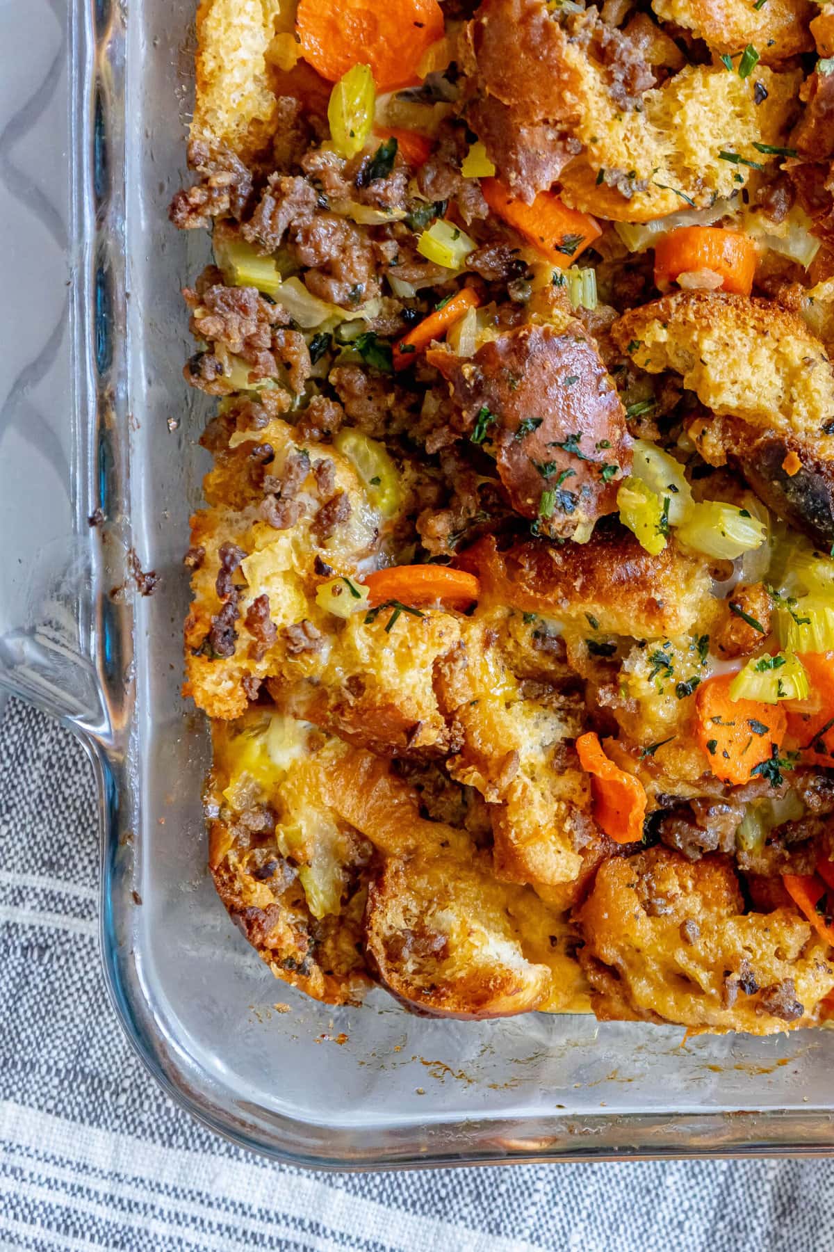 picture of cheeseburger stuffing in a glass tray on a table with carrots and herbs on top 