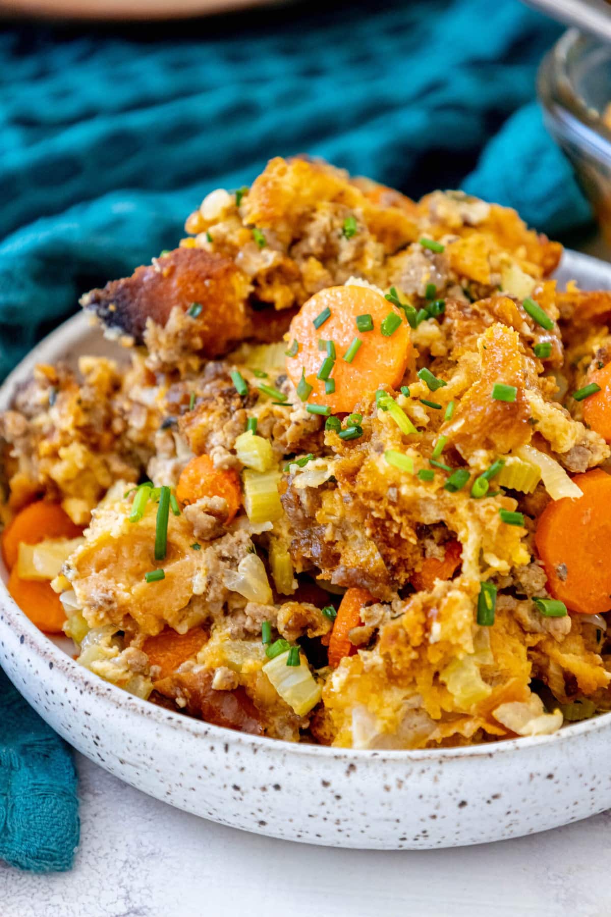 picture of cheeseburger stuffing in a glass tray on a table with carrots and herbs on top 