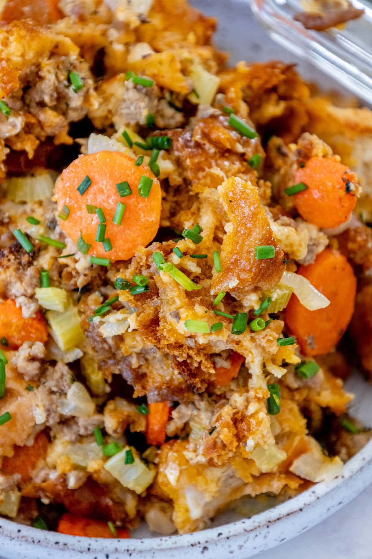 picture of cheeseburger stuffing in a glass tray on a table with carrots and herbs on top 