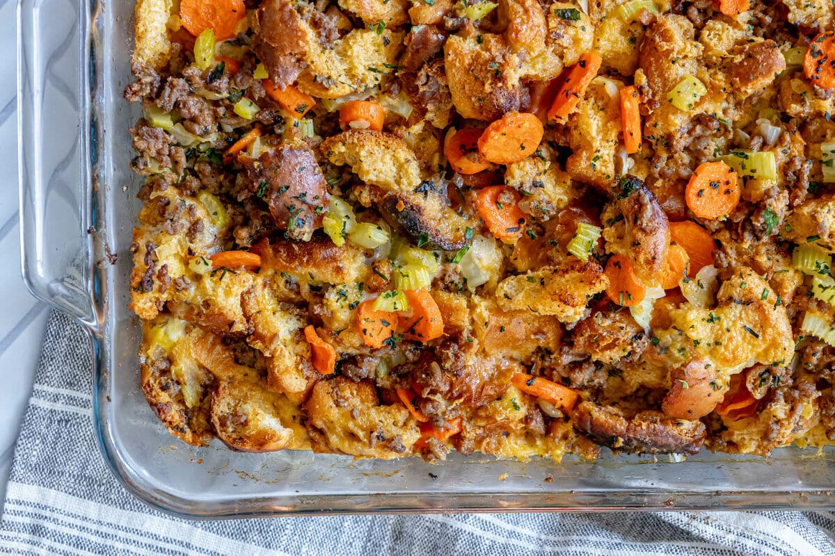 picture of cheeseburger stuffing in a glass tray on a table with carrots and herbs on top 