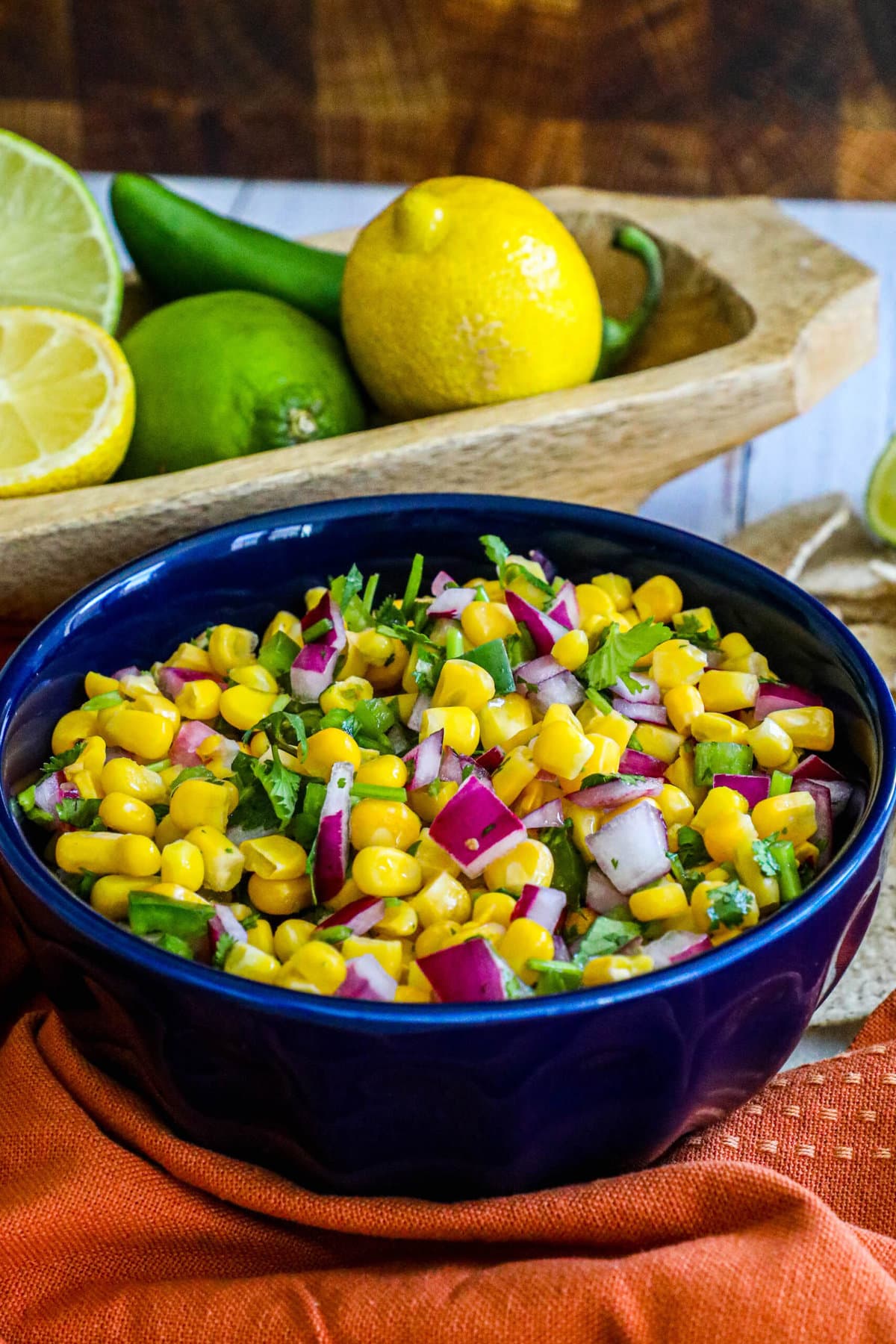 picture of corn salsa in a blue bowl with onions, jalapenos, cilantro