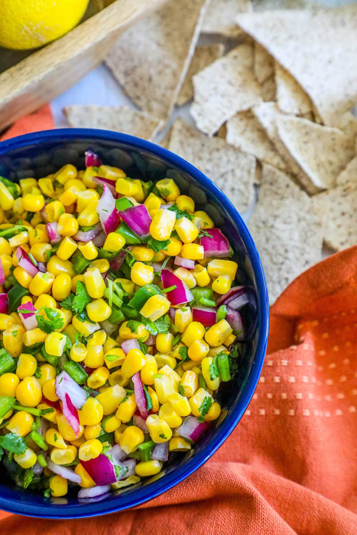 picture of corn salsa in a blue bowl with onions, jalapenos, cilantro