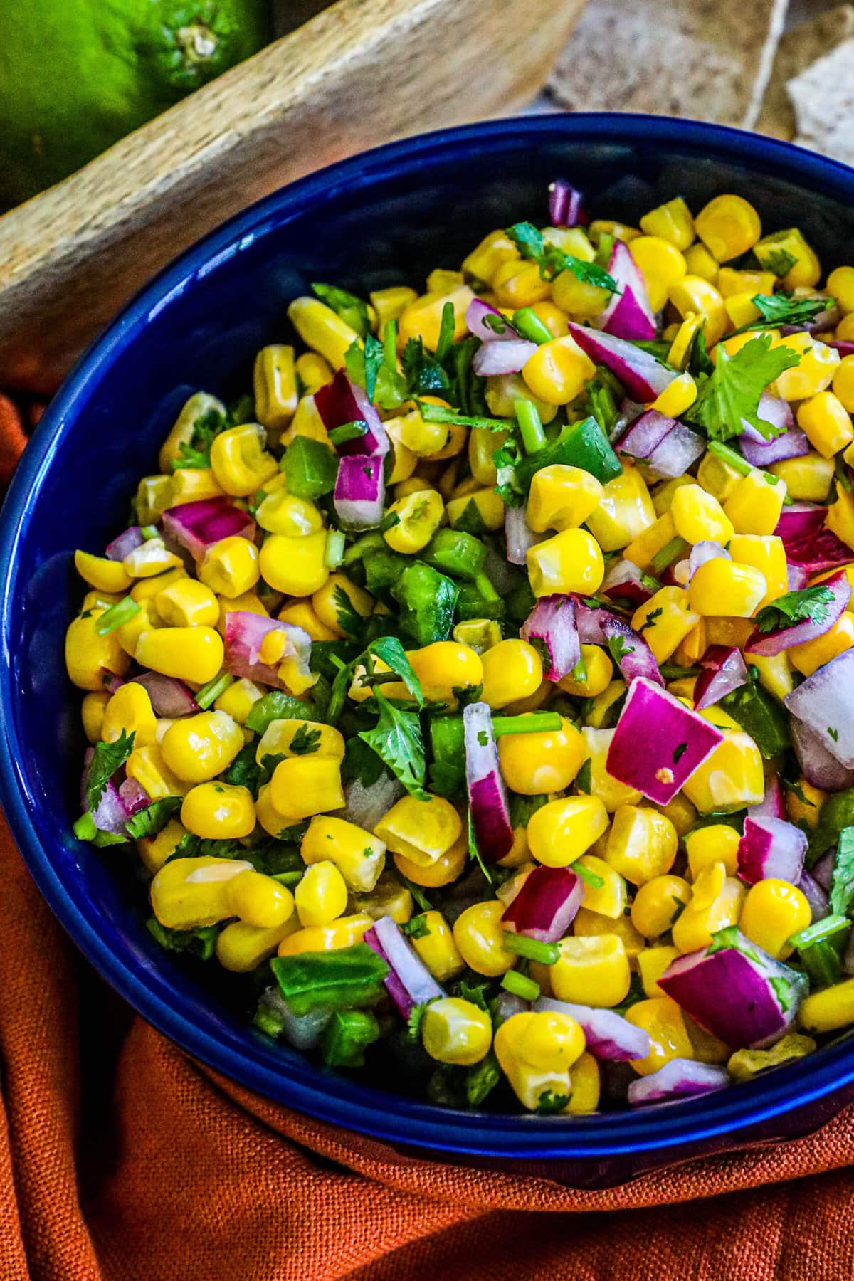 picture of corn salsa in a blue bowl with onions, jalapenos, cilantro