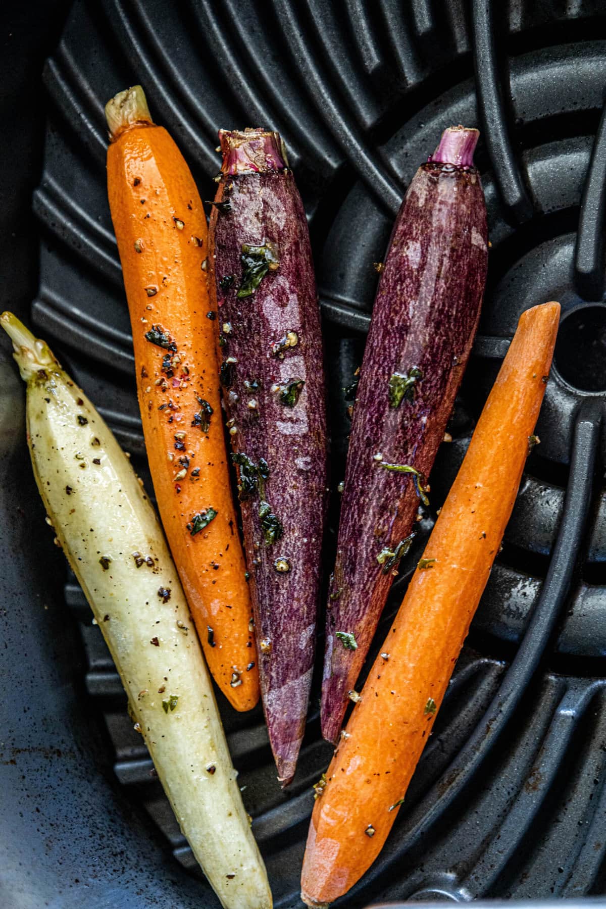 Grilled carrots in a black frying pan.