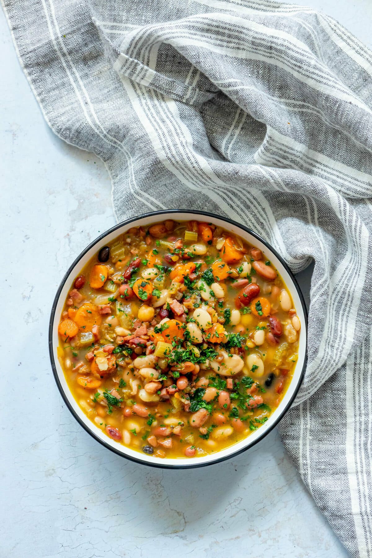 picture of soup in a bowl with ham, beans, celery, and parsley on top 