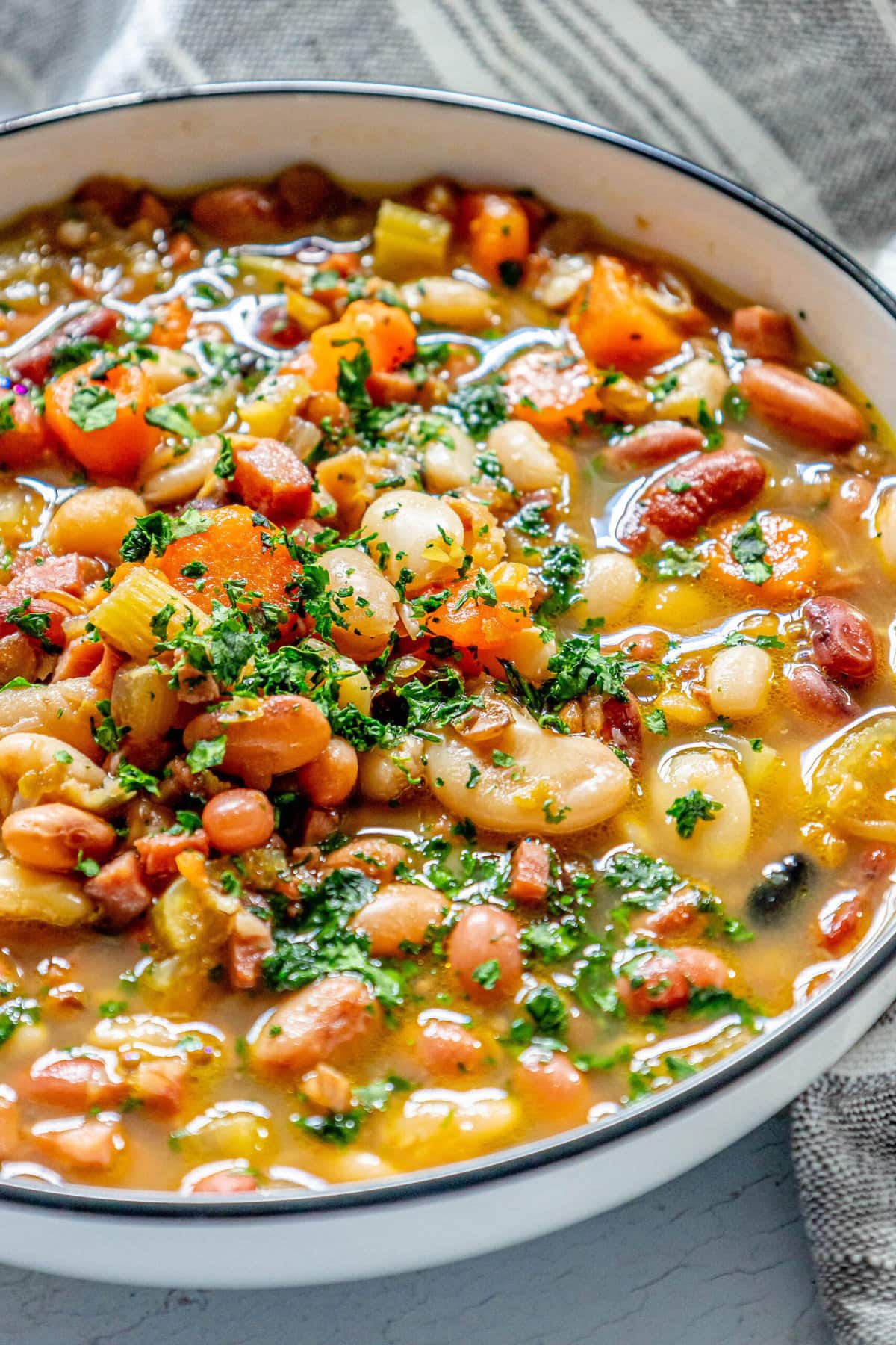 picture of soup in a bowl with ham, beans, celery, and parsley on top 