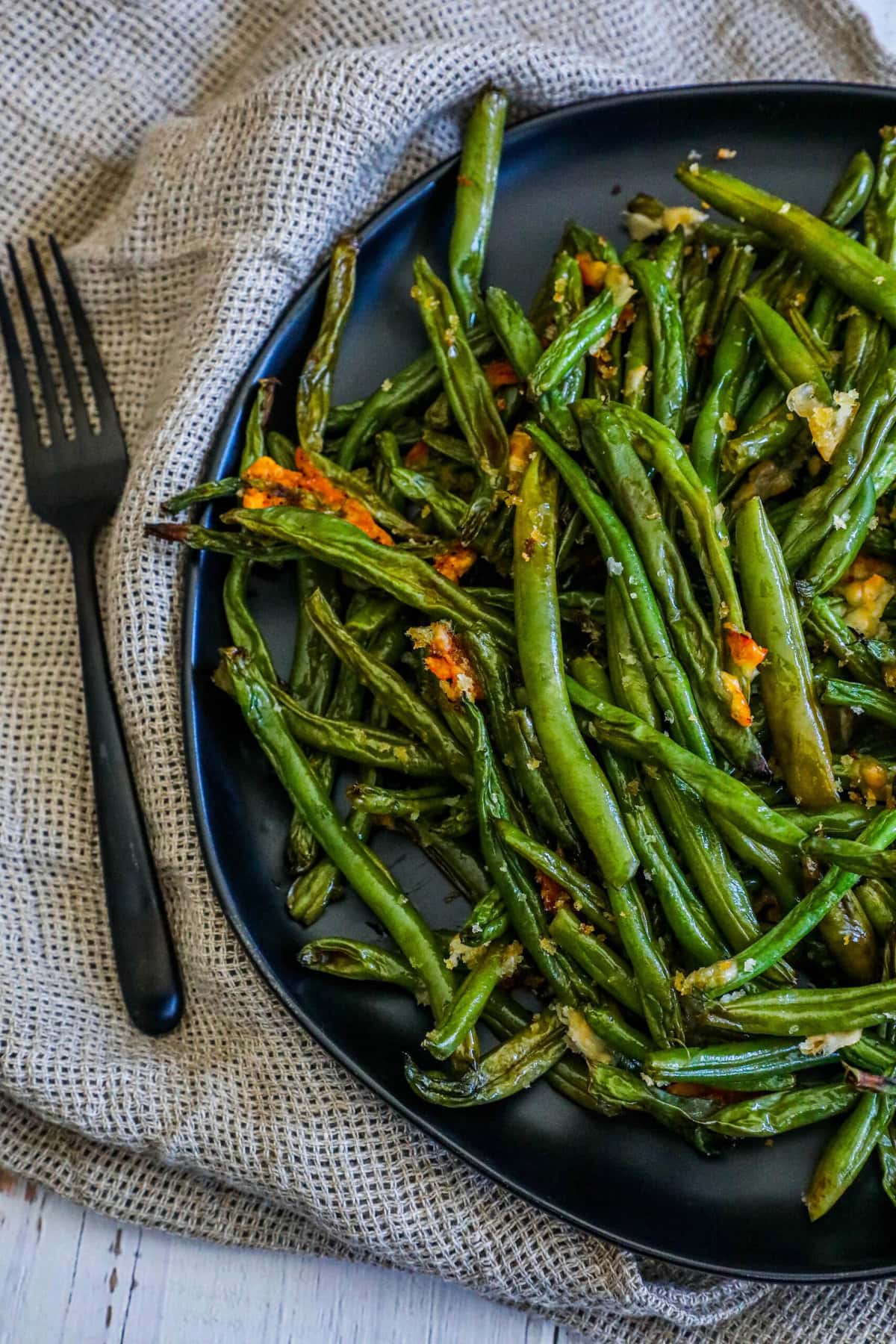 picture of parmesan roasted green beans on a black plate on a table