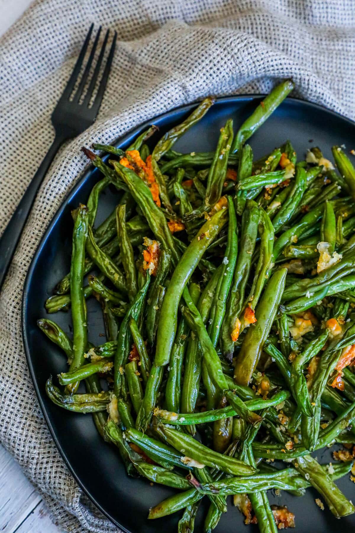 picture of parmesan roasted green beans on a black plate on a table