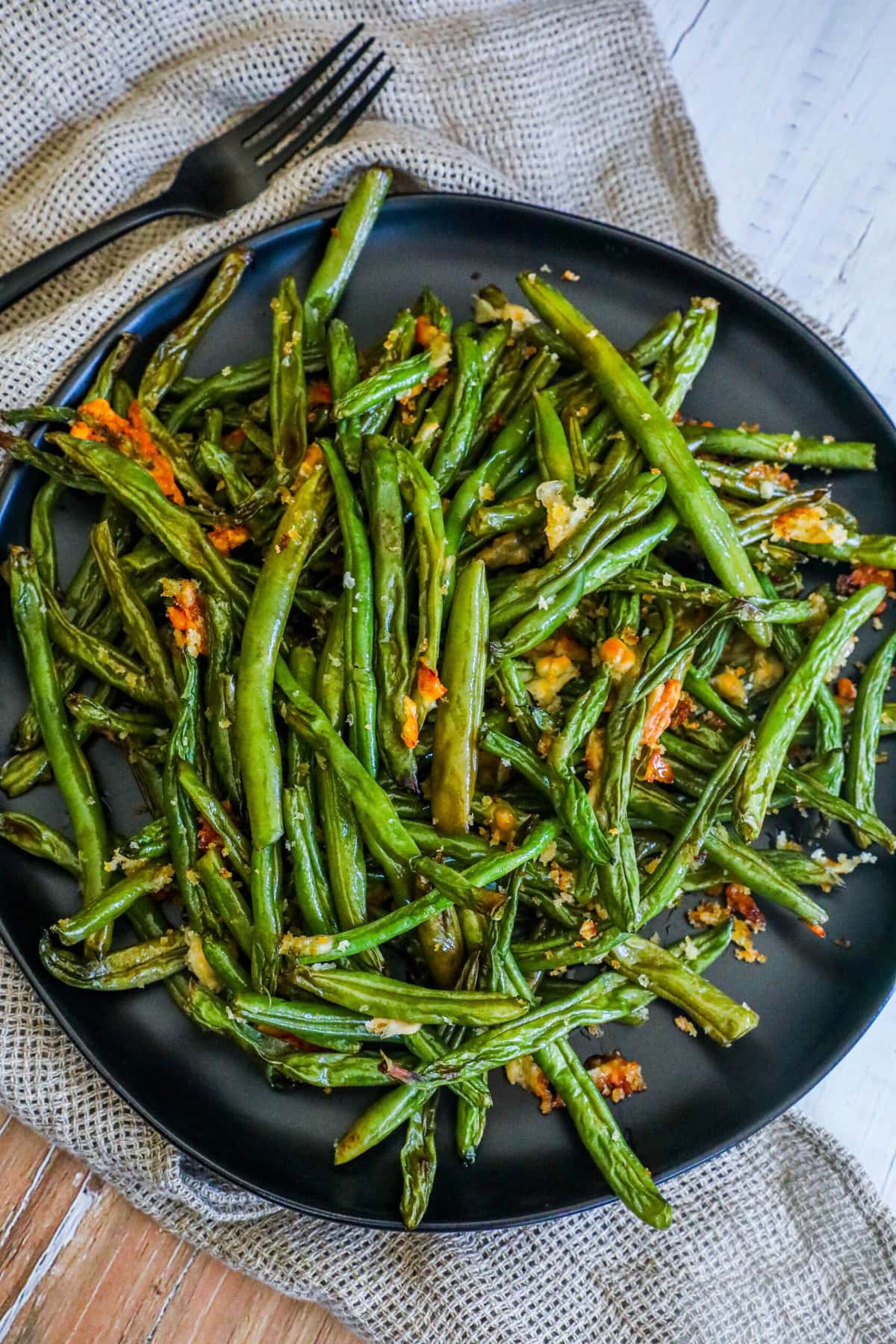 picture of parmesan roasted green beans on a black plate on a table