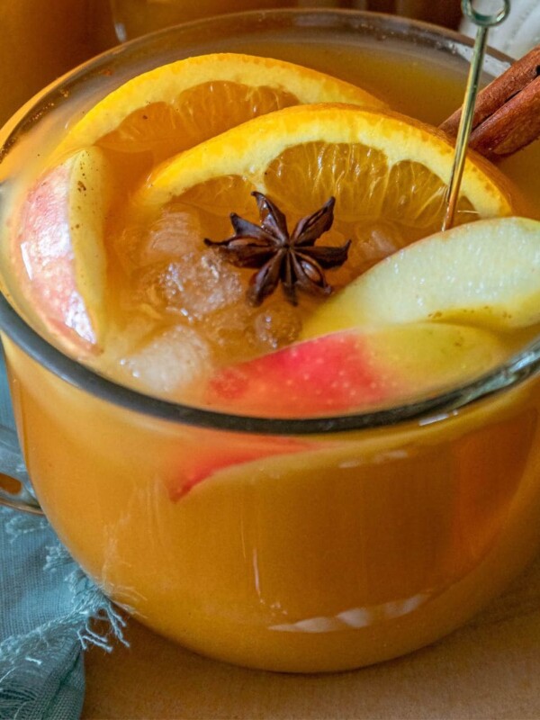 pumpkin punch in a clear mug with ice, apples, oranges, cinnamon, anise in the mug