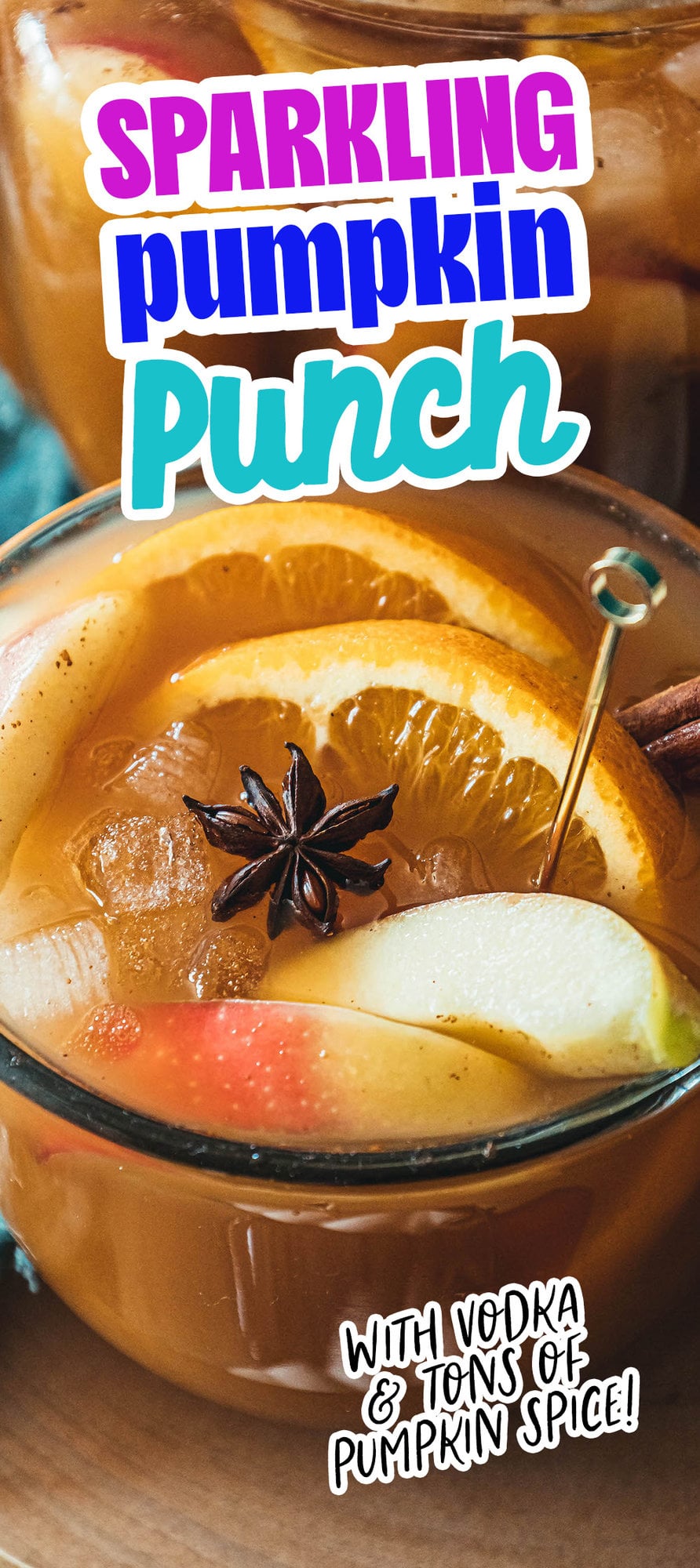 pumpkin punch in a clear mug with orange slices, apple slices, cinnamon stick, ice cubes, and a star of anise in it