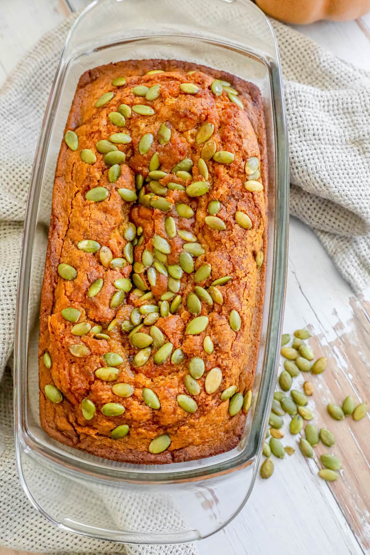 pumpkin bread with pumpkin seeds baked onto the top sliced on a table