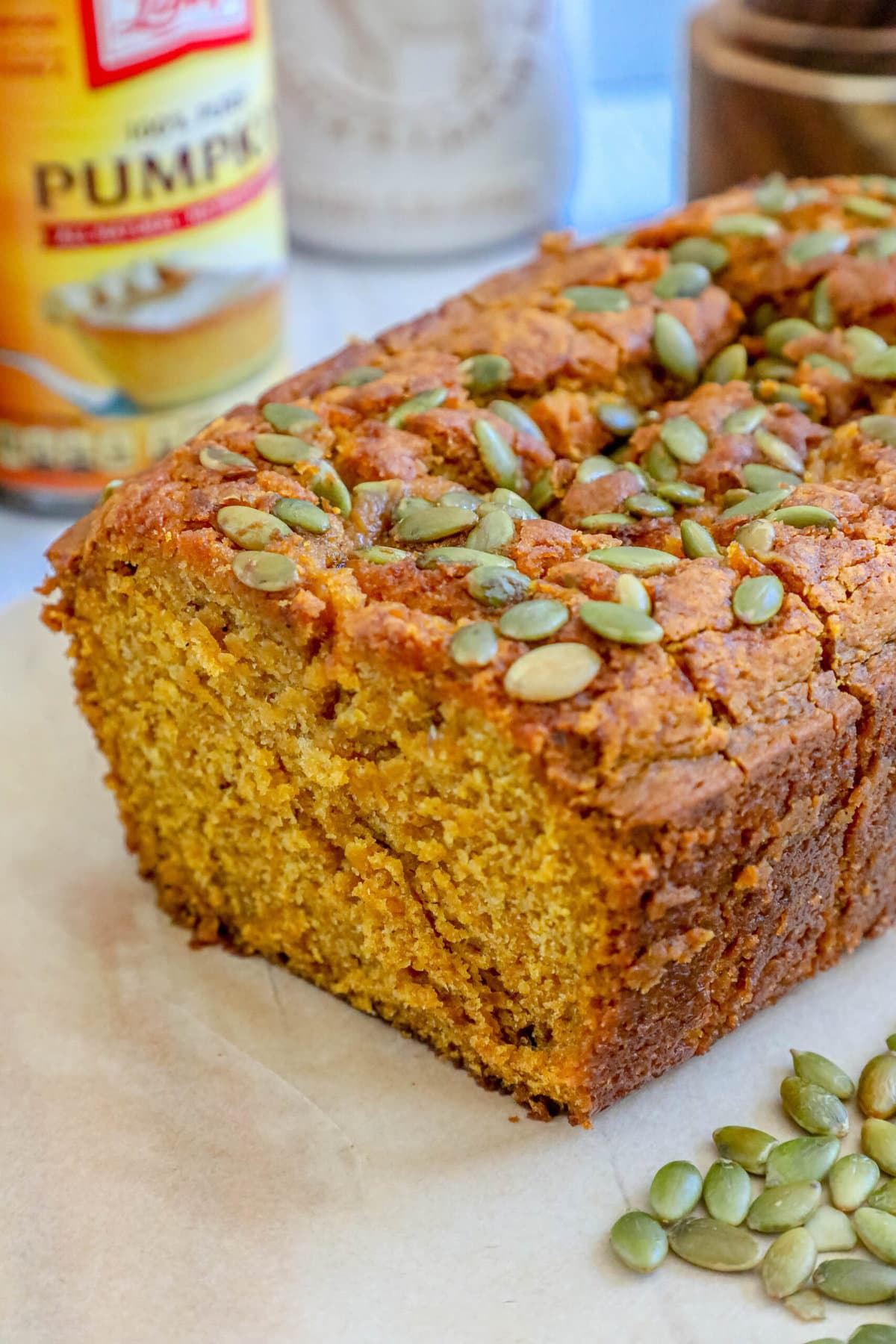 picture of pumpkin bread with pumpkin seeds baked onto the top sliced on a table