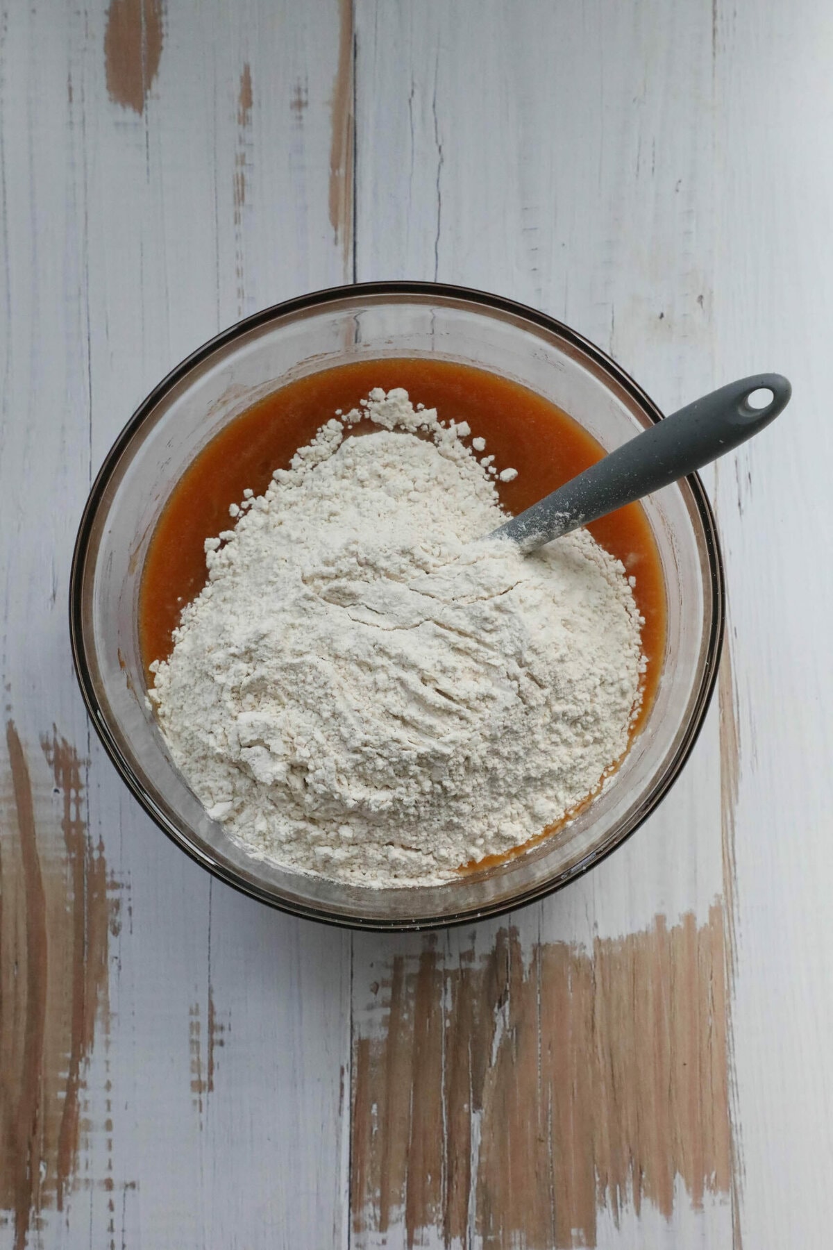 A Copycat Starbucks Pumpkin Bread recipe displayed with a bowl of flour and a spoon on a wooden table.