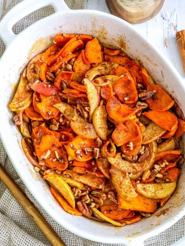 picture of baked cinnamon apples and sweet potatoes in a white baking dish with a spoon on a table