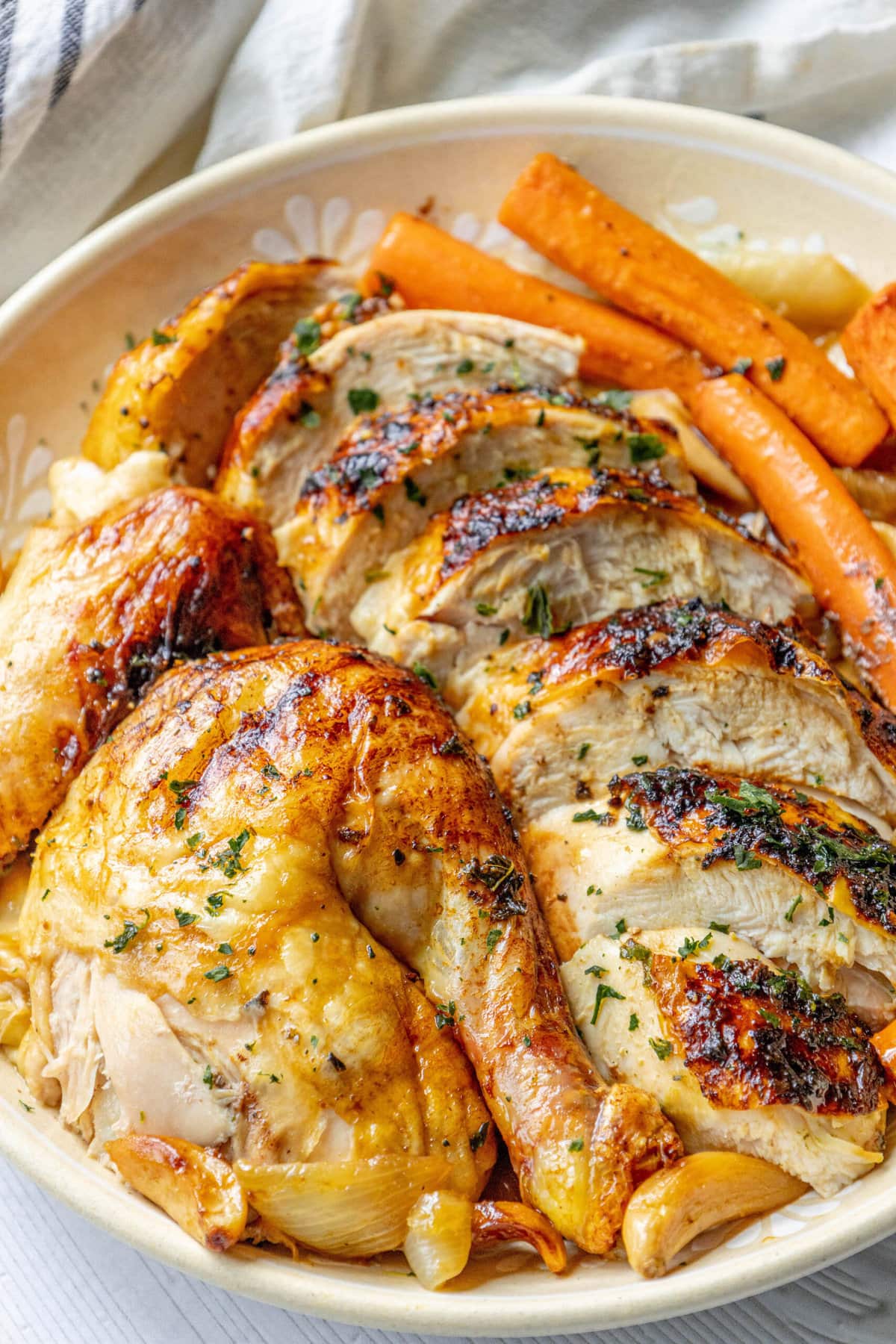 picture of sliced roast chicken on a platter with roasted carrots and onions