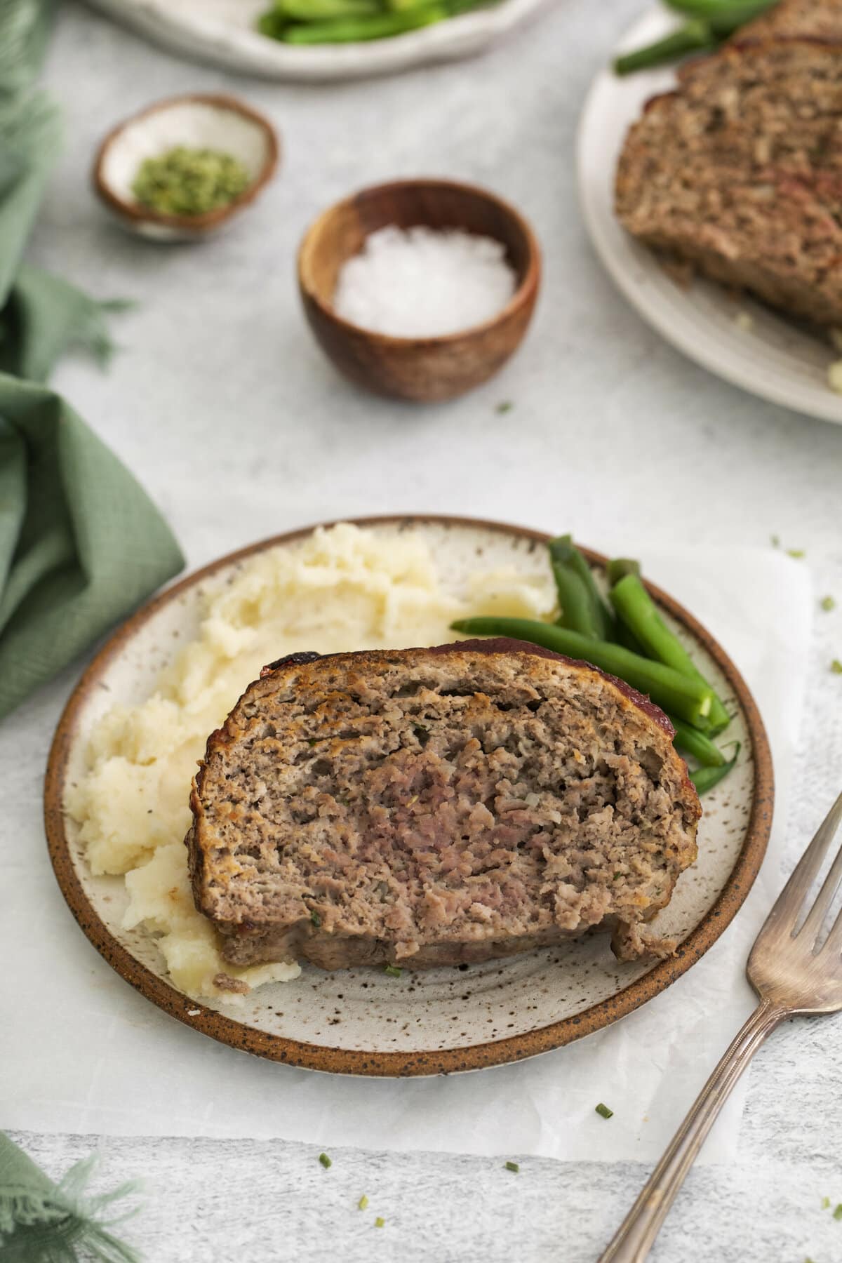 meatloaf on a plate with potatoes and green beans