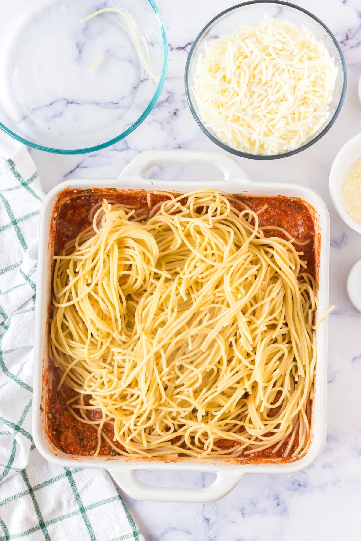 picture of spaghetti and pasta sauce in a white casserole dish being mixed