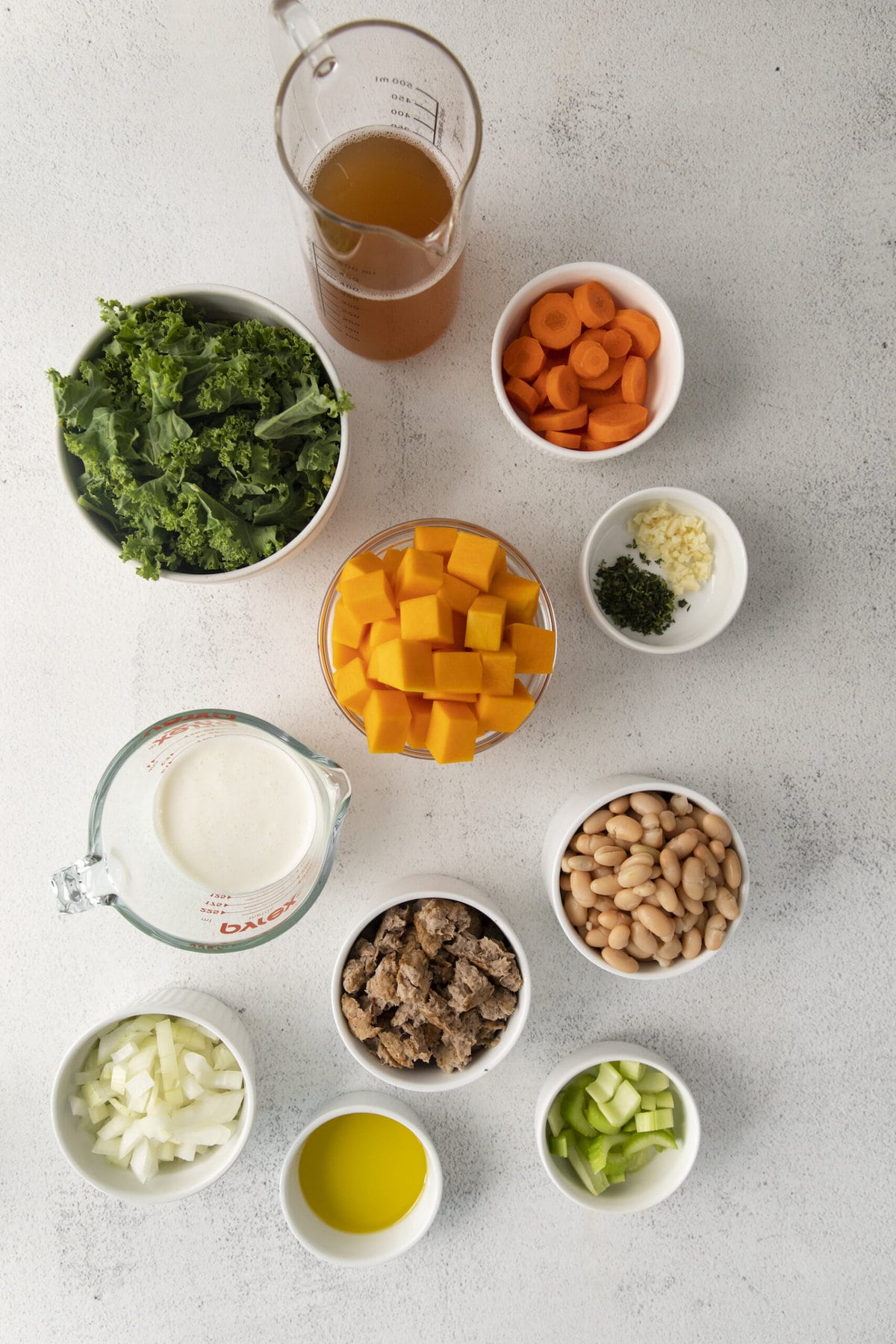 kale, cooked ground turkey, carrots, beans, cream, and vegetables in cups on a table