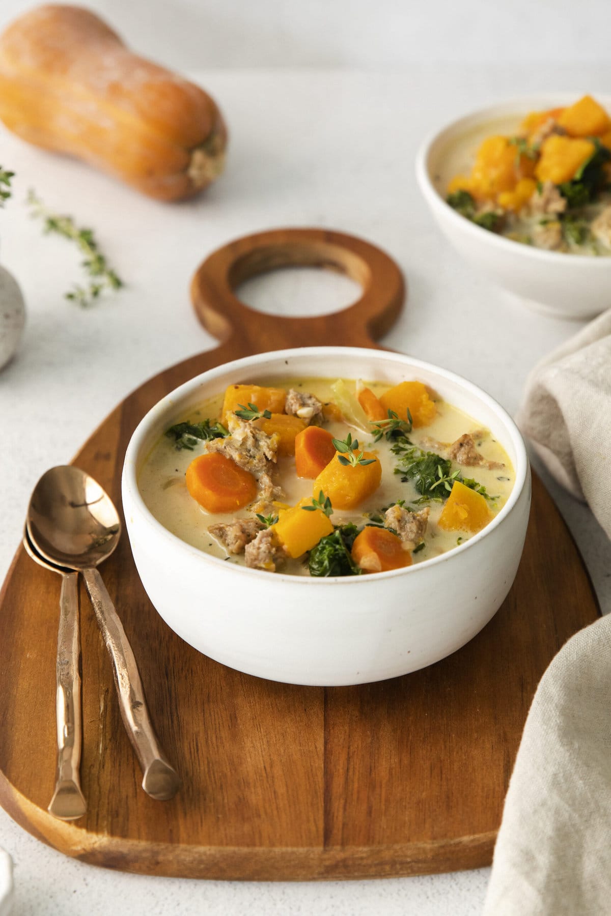  creamy turkey and butternut squash chili with carrots, thyme, kale, and peppers in a white bowl on a table