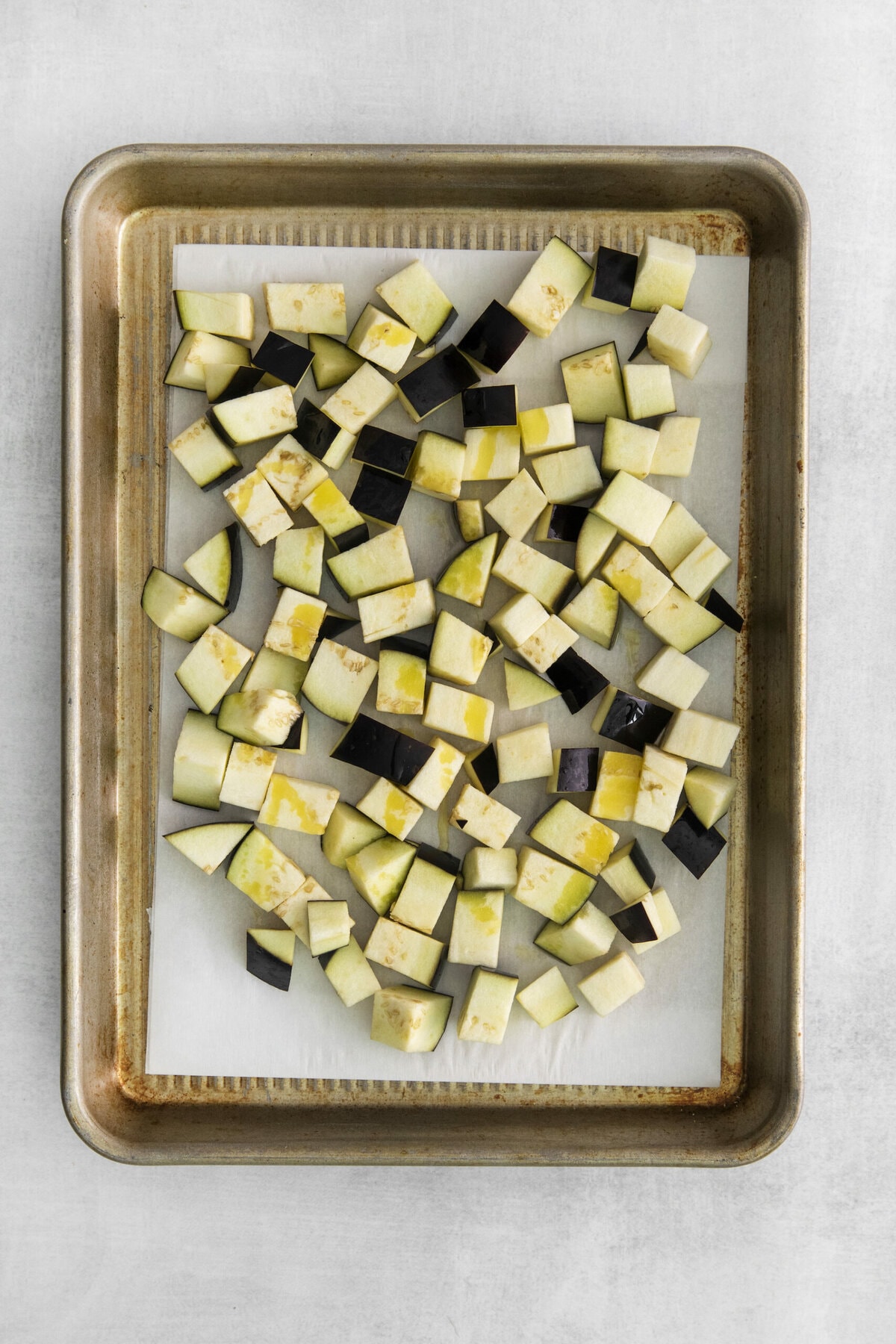 picture of cubed raw eggplant on a baking sheet lined with parchment paper