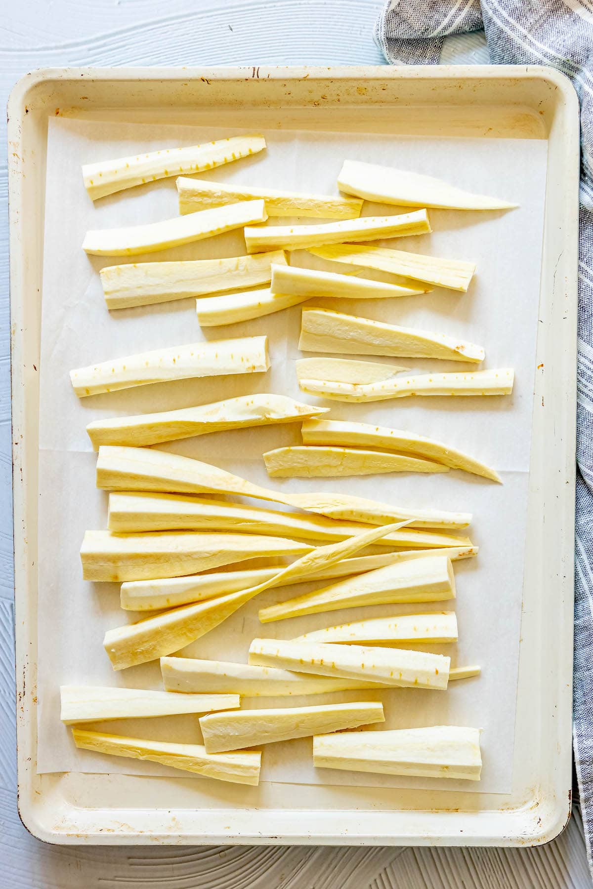 peeled and chopped parsnips on a baking sheet lined with parchment paper
