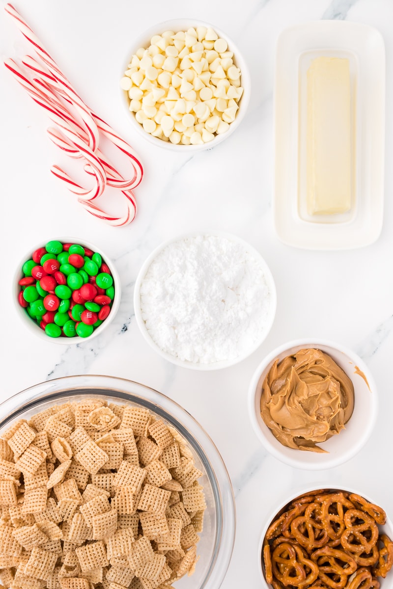 A bowl of Christmas Chex Mix Muddy Buddies and candy canes.