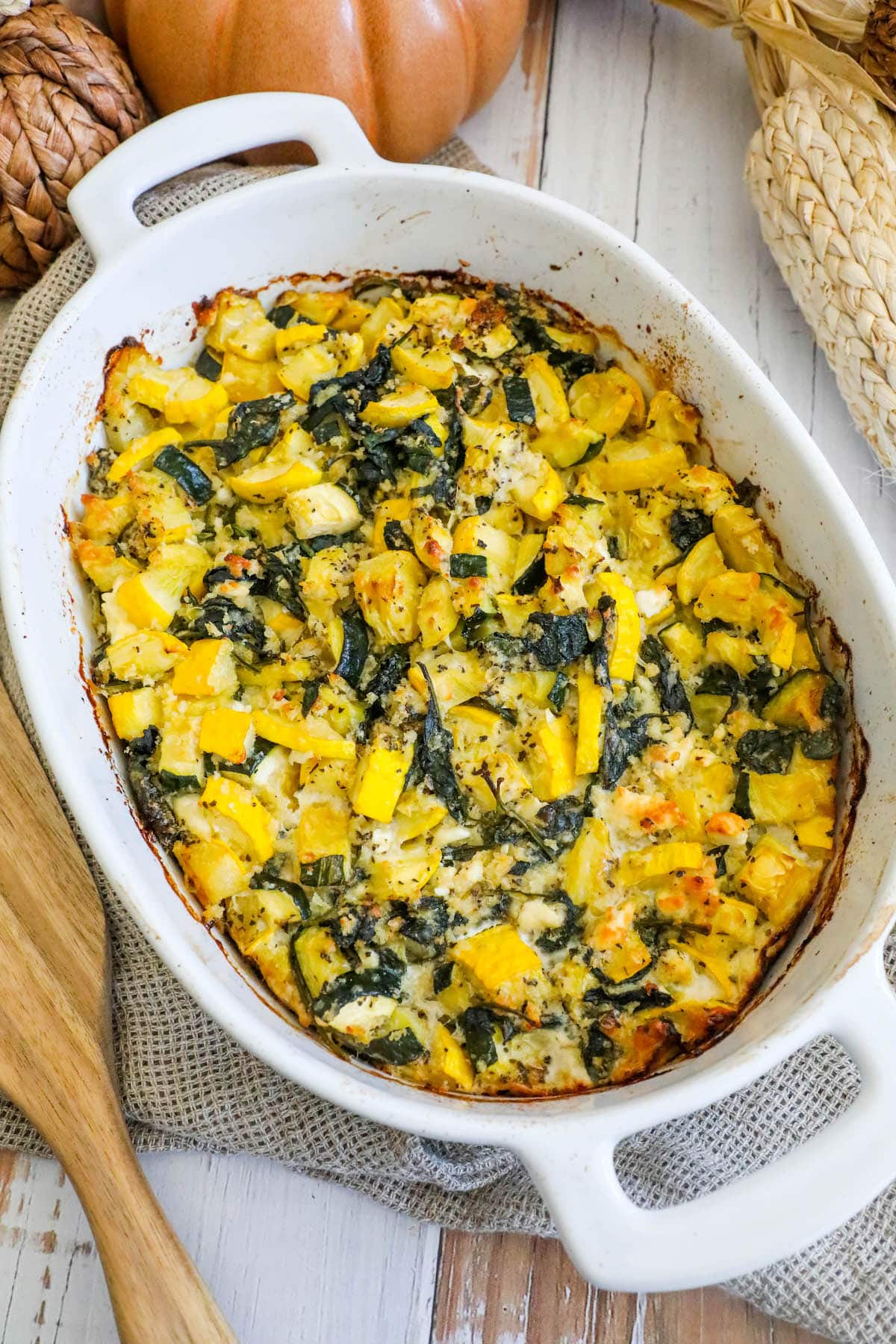 picture of spinach and zucchini feta baked casserole in a white dish on a table