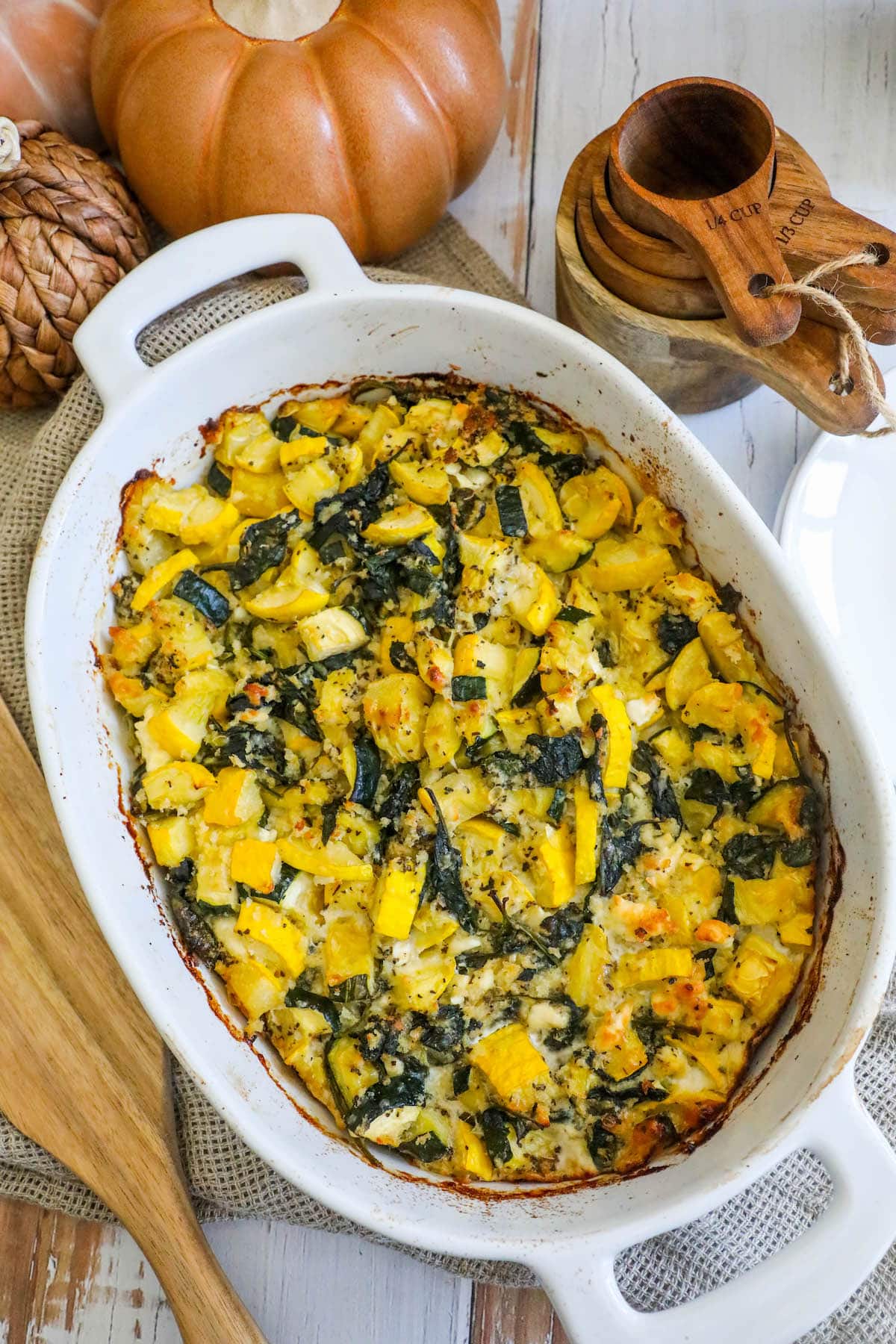 picture of spinach and zucchini feta baked casserole in a white dish on a table