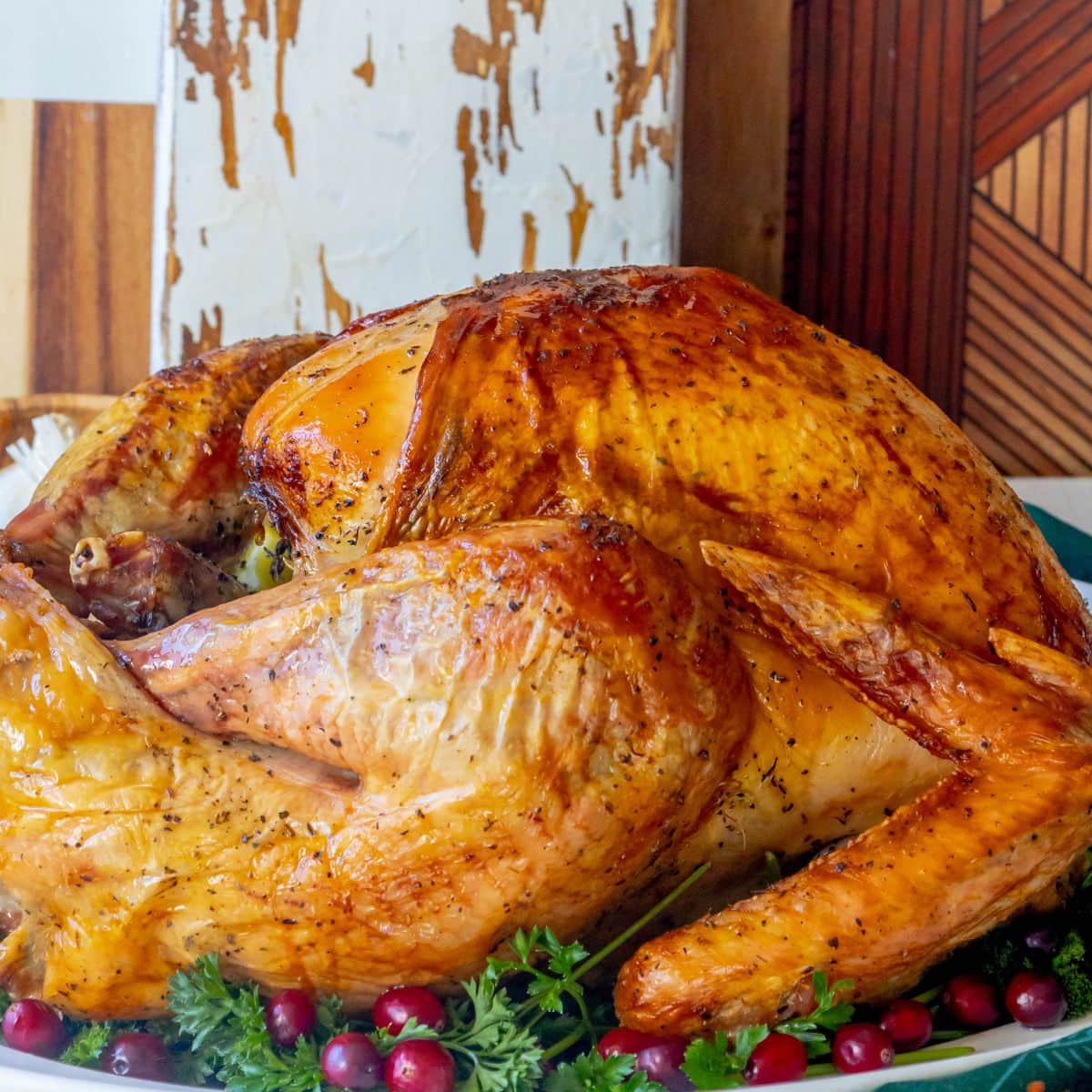 picture of a roasted turkey on a white plate with parsley and cranberries on a plate