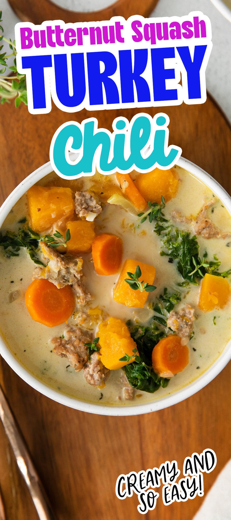 picture of creamy turkey and butternut squash chili with carrots, thyme, kale, and peppers in a white bowl on a table